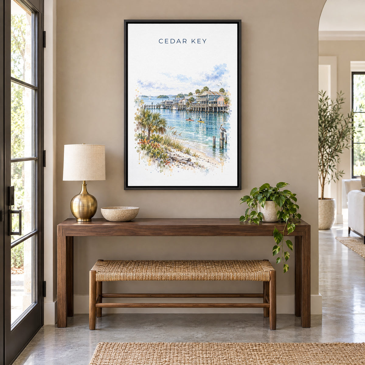 Cedar Key, Florida watercolor print as a black floater canvas above a walnut console and woven bench in an entryway