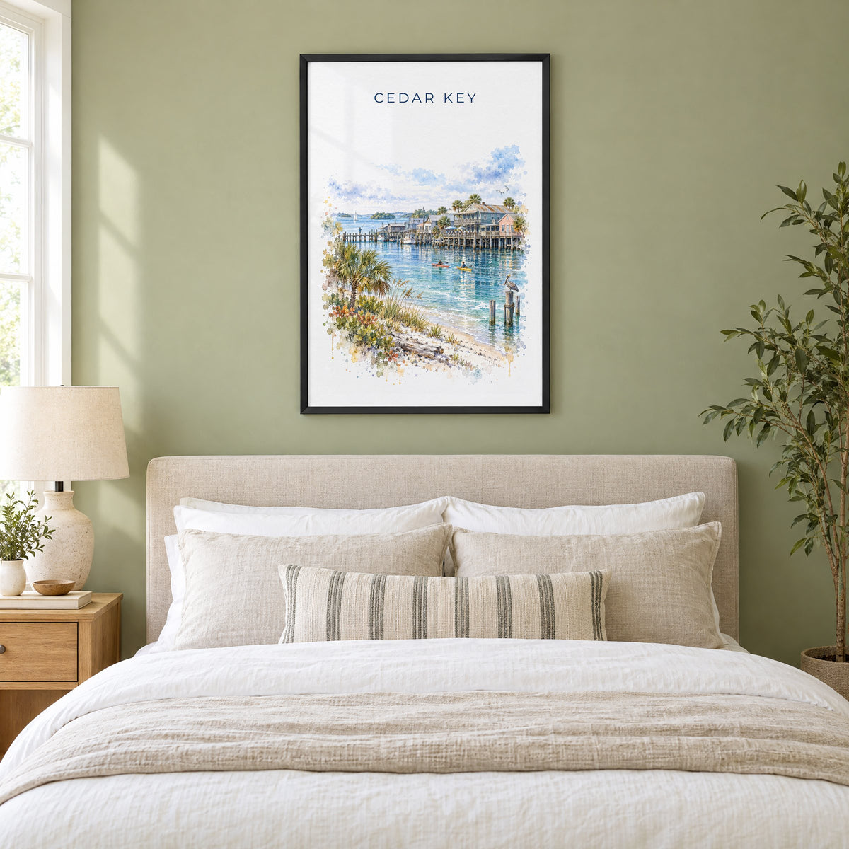 Cedar Key, Florida watercolor print in a black frame above an upholstered headboard in a sage green bedroom