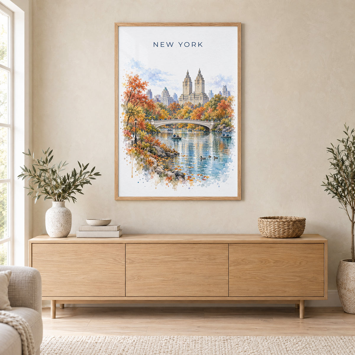 Central Park watercolor print in an oak frame above a light wood sideboard in a Scandinavian living room