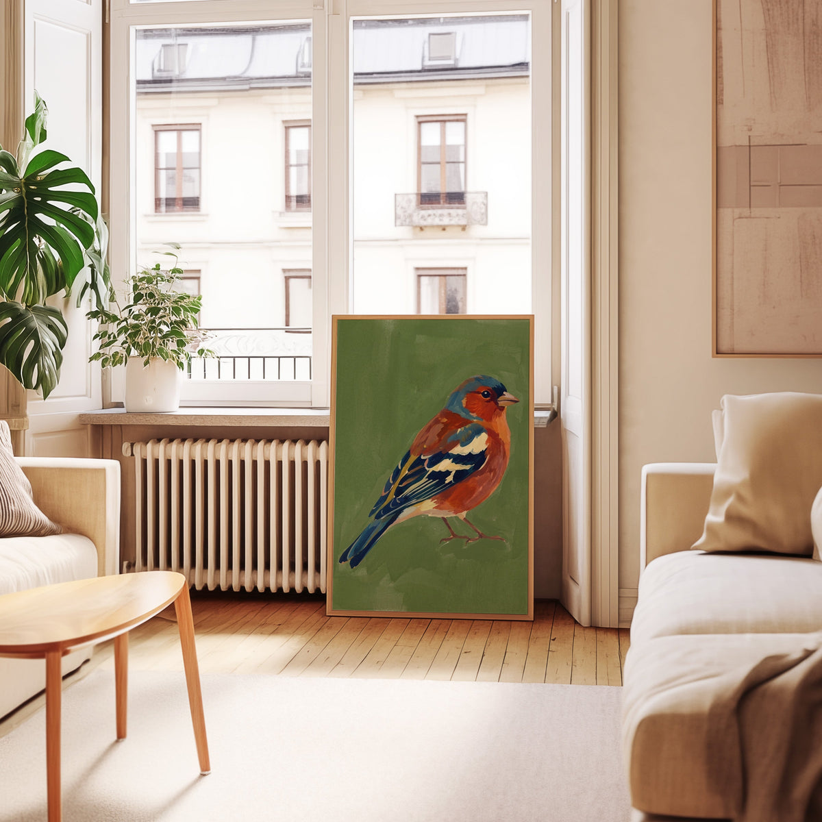 Moss green bird print in an oak frame leaning below tall French windows