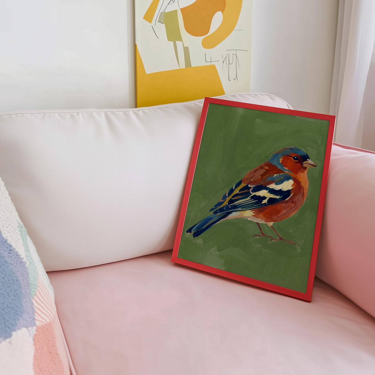 Red breasted songbird print shown in a red frame leaning on a blush pink sofa