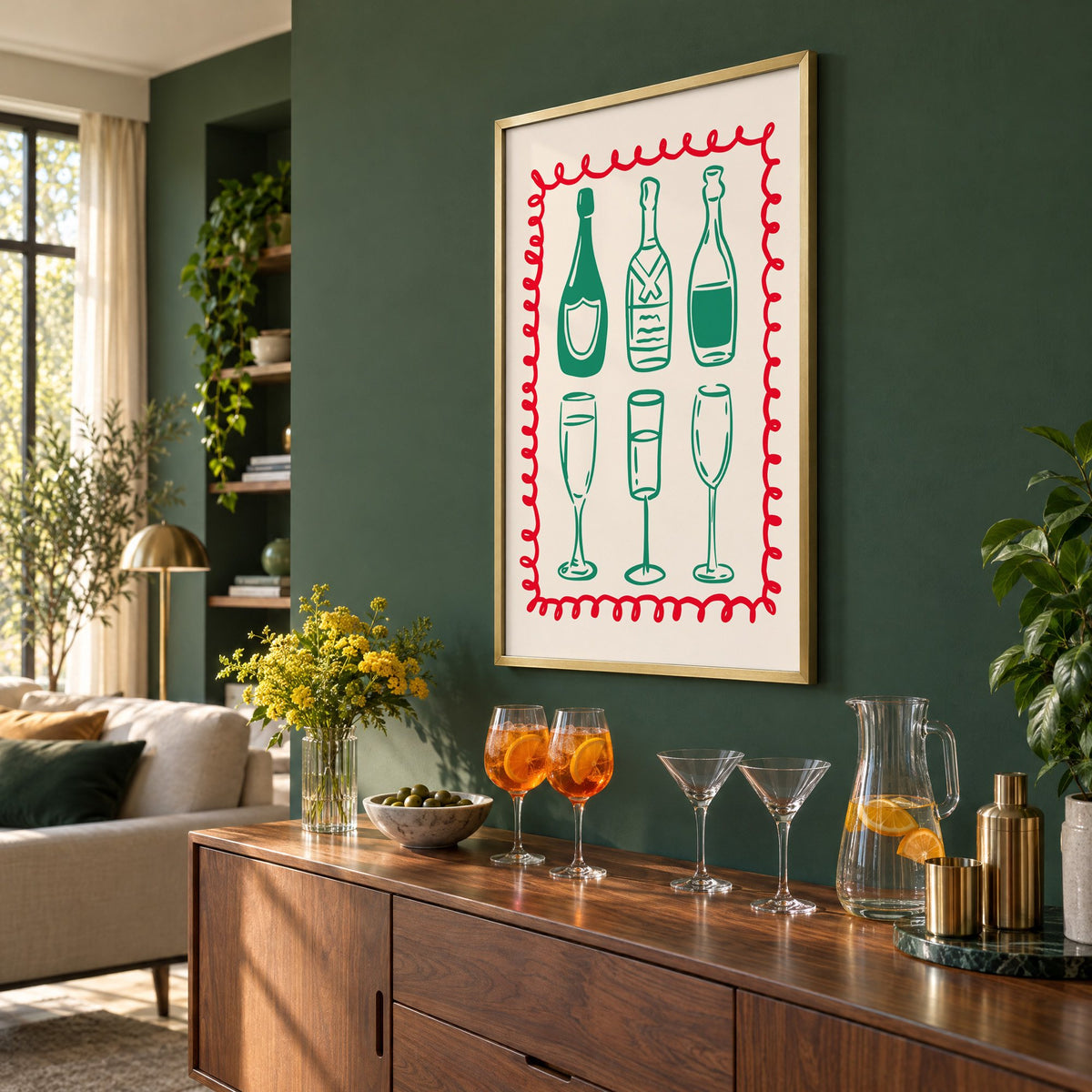 Green champagne bottles and glasses squiggle frame print in a brass frame on a bottle green wall above a sideboard with spritz and martini glasses, seen at an angle
