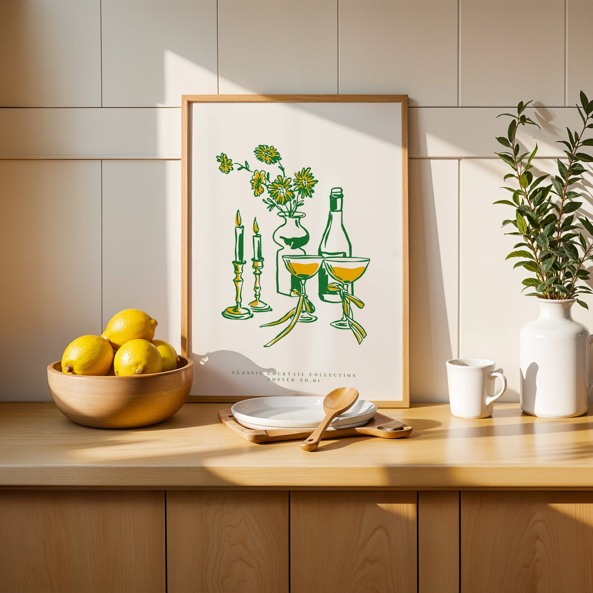 Champagne coupes and daisies print in a slim oak frame beside a bowl of lemons