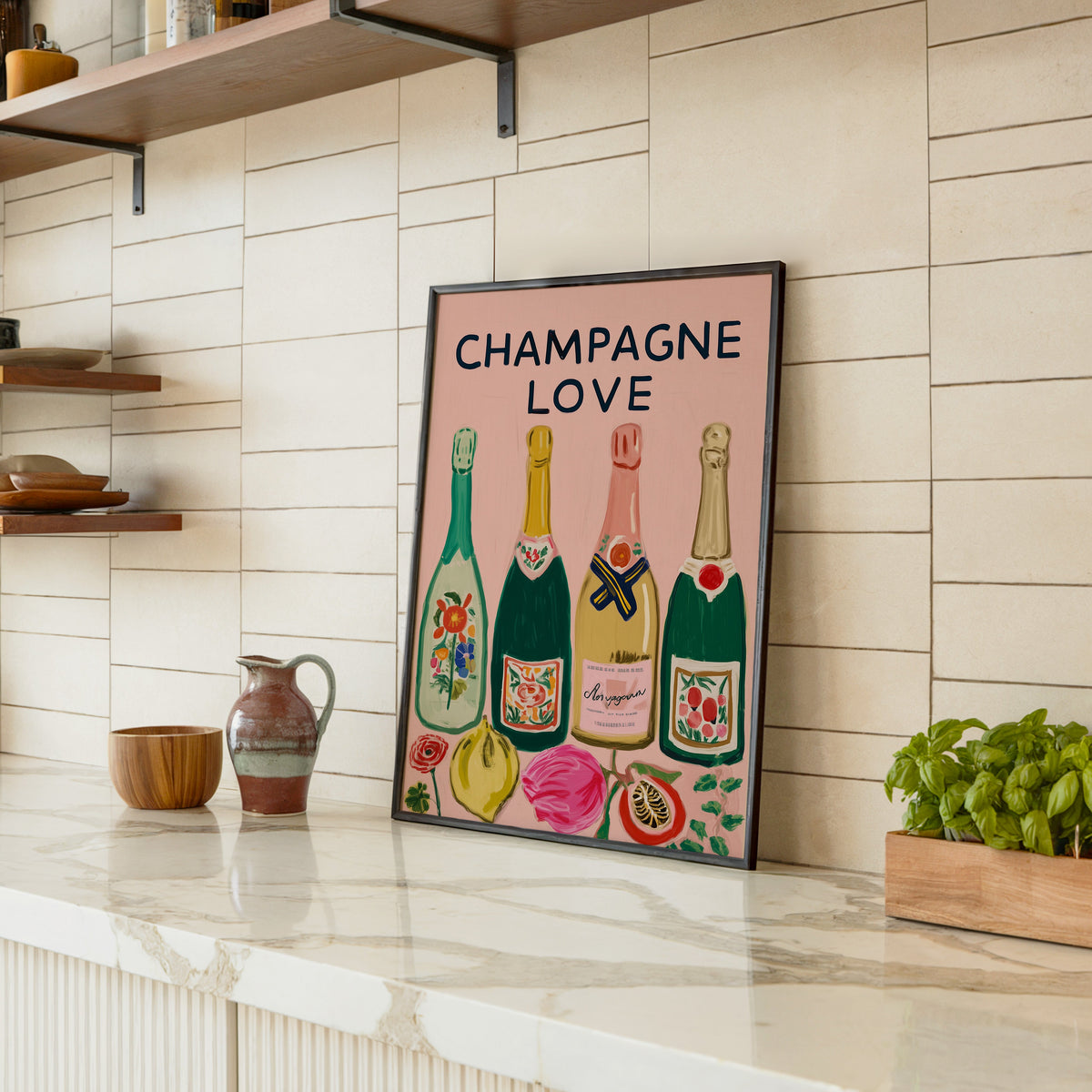 Champagne Love print in a black frame leaning on a marble counter in a tiled kitchen