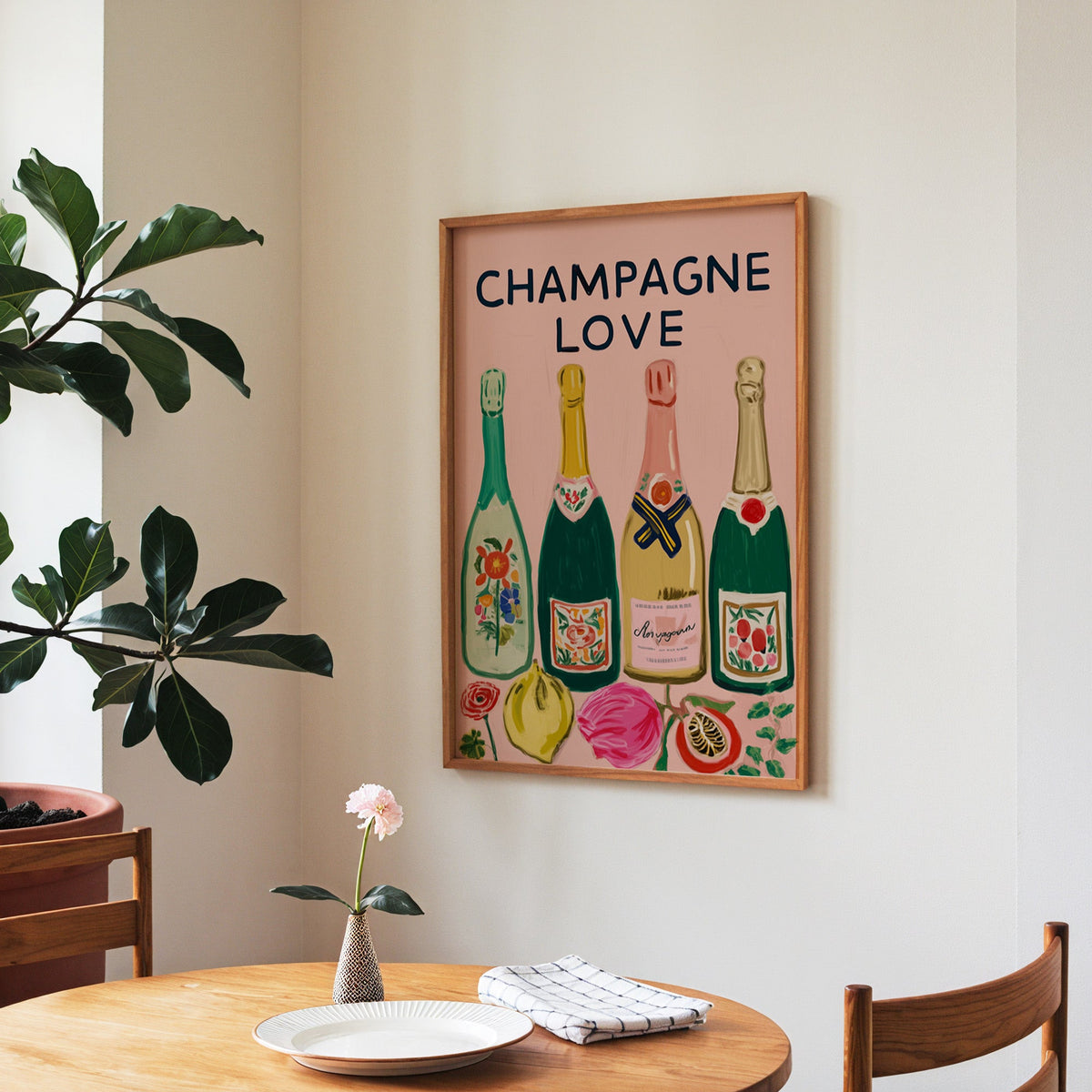 Champagne Love print in a walnut frame above a round table beside a fiddle-leaf fig