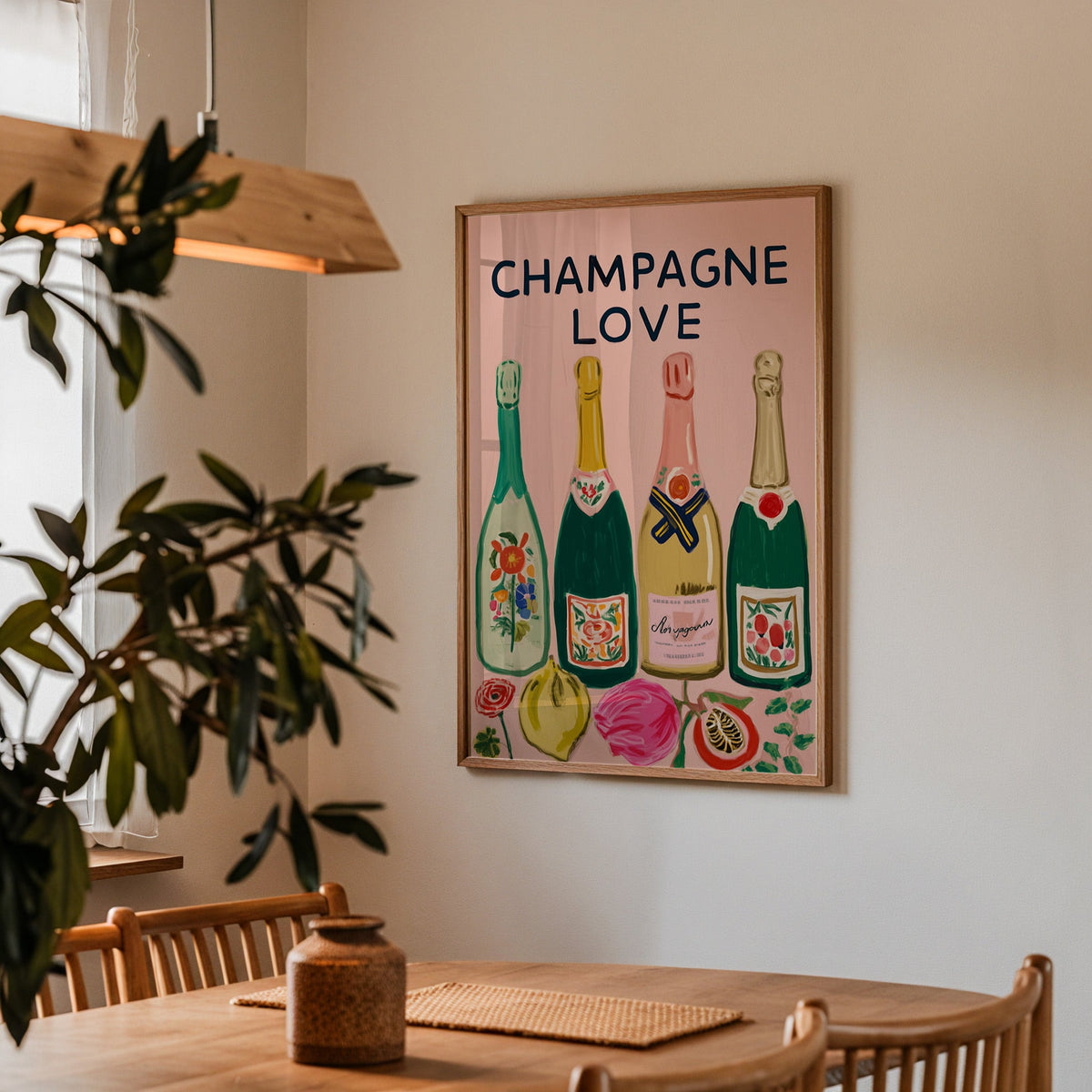 Champagne Love print in a walnut frame above a dining table with olive branches