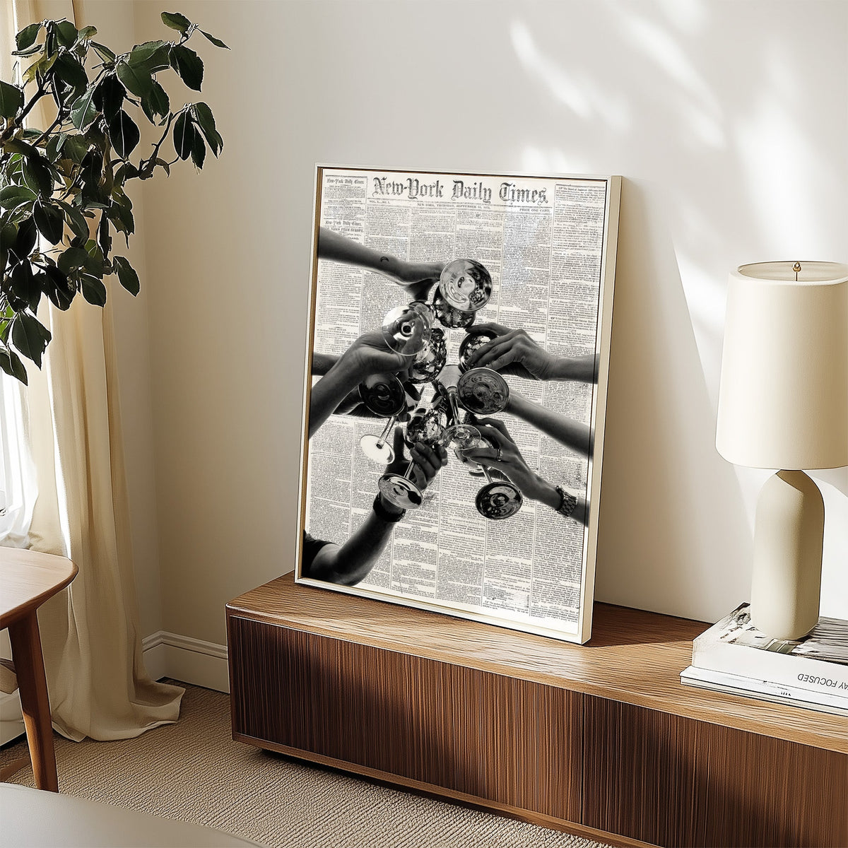 Champagne toast collage on 1851 newspaper print in a white frame on a walnut sideboard beside a ceramic lamp