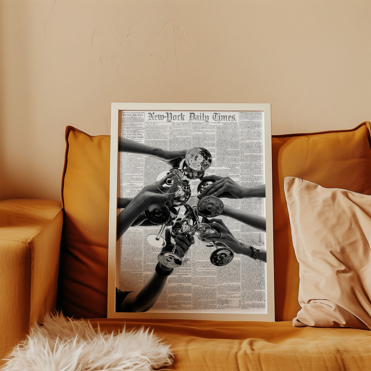 Champagne toast collage on 1851 newspaper print in a white frame leaning on a mustard velvet sofa