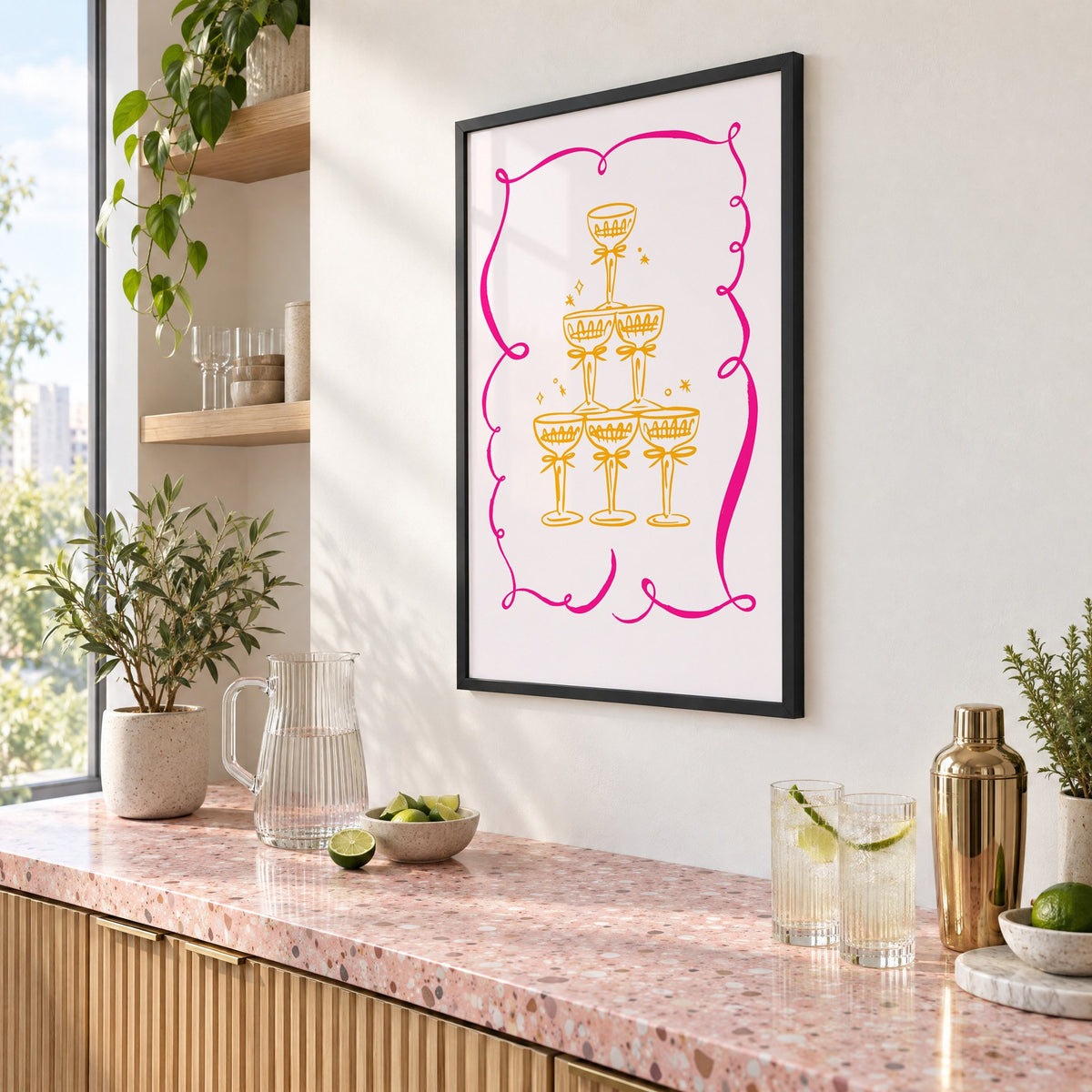 Champagne tower pink ribbon frame print in a black frame above a pink terrazzo cocktail counter with limes, seen at an angle