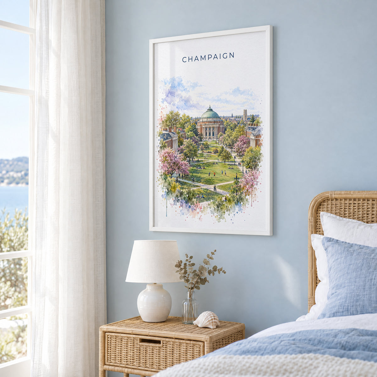 Champaign watercolor print in a white frame on a pale blue wall beside a rattan bed in a coastal bedroom