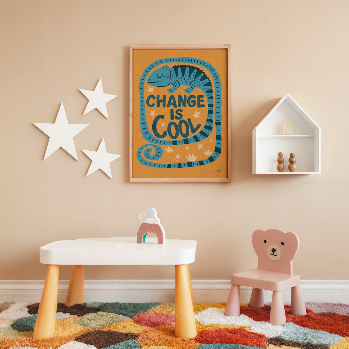 Change is cool chameleon orange nursery print in an oak frame on a peach wall above a kids table with wall stars