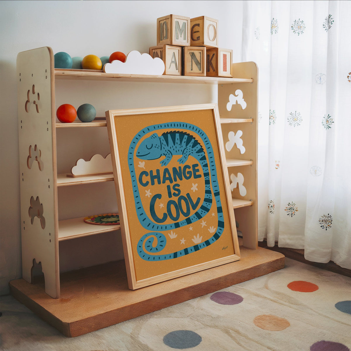 Change is cool chameleon orange nursery print in an oak frame leaning on a toy shelf with wooden letter blocks