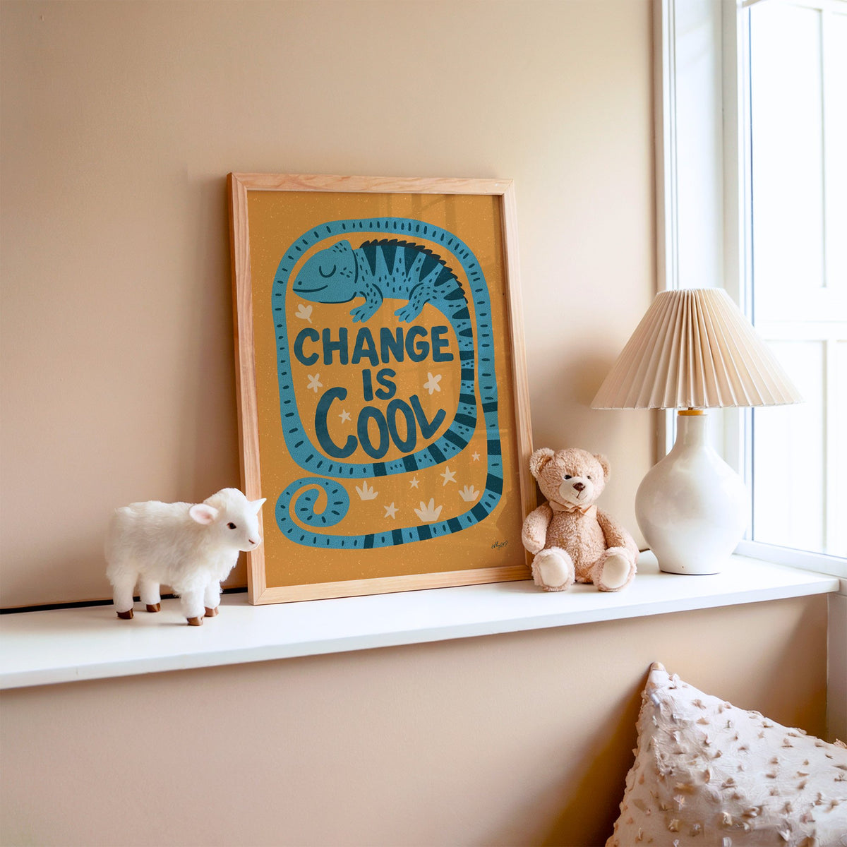 Change is cool chameleon orange nursery print in an oak frame on a window ledge with a toy lamb and teddy