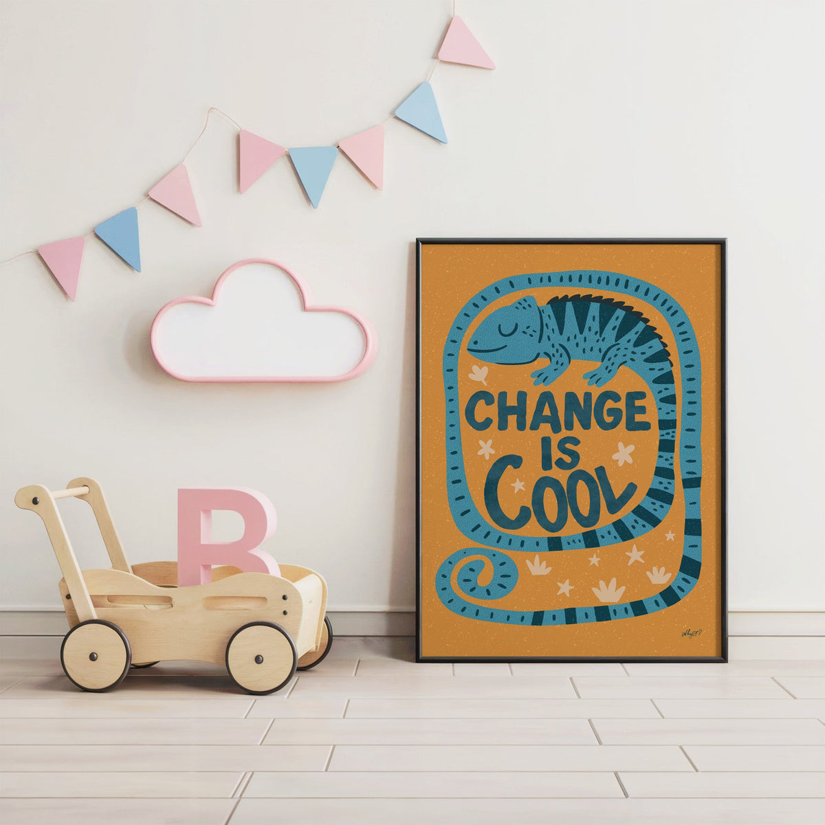 Change is cool chameleon orange nursery print in a black frame under pastel bunting by a wooden baby walker