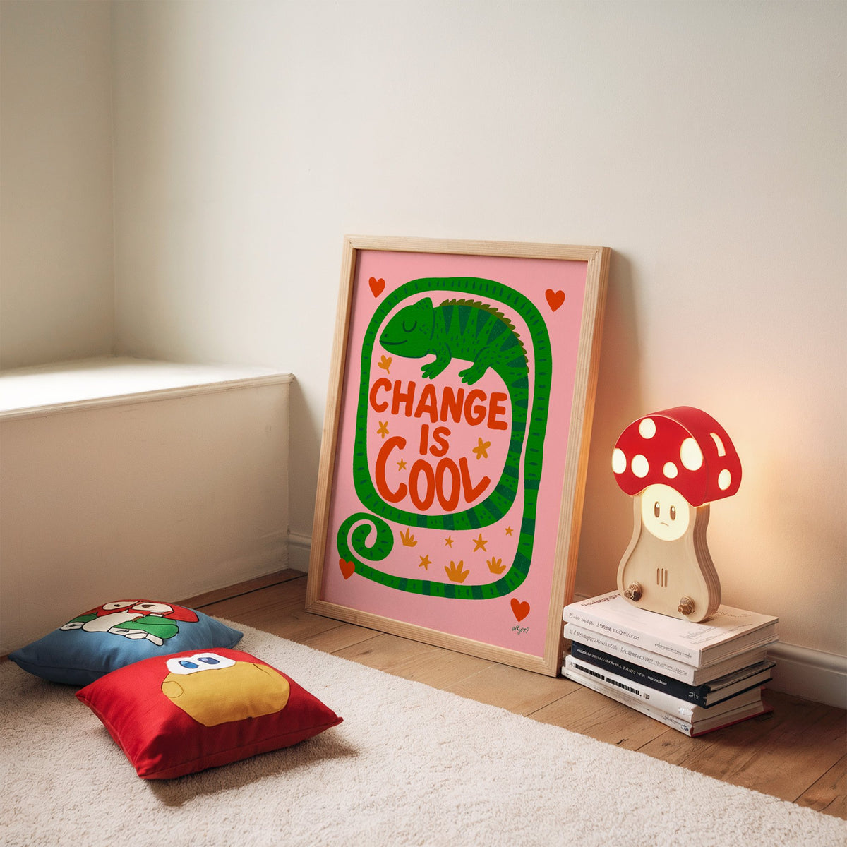 Change is cool chameleon pink nursery print in an oak frame leaning on a rug beside a mushroom lamp and floor cushions
