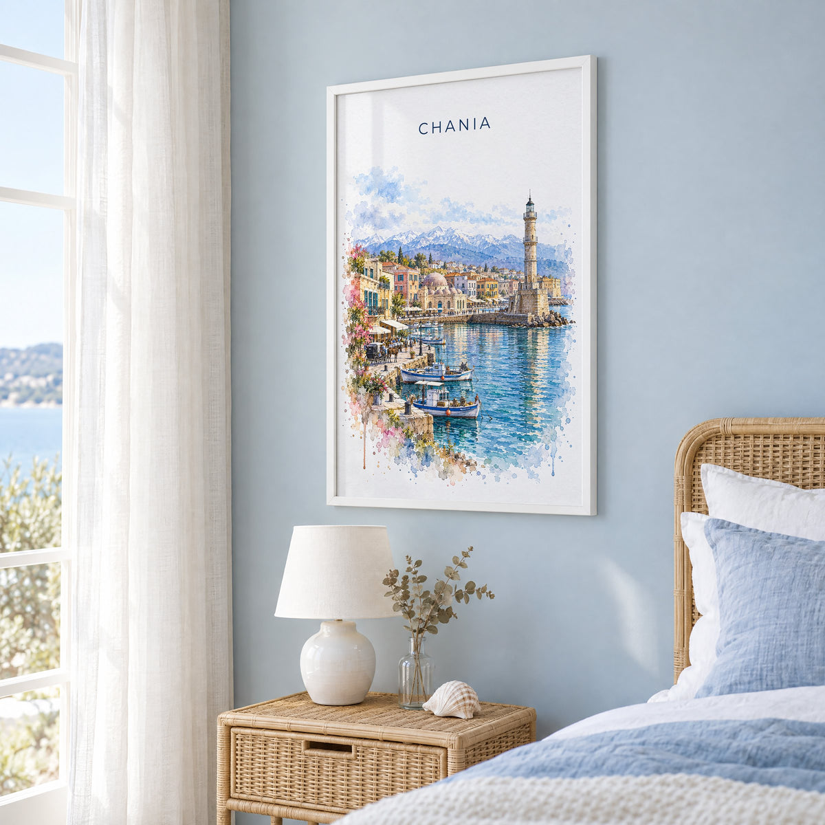 Chania watercolor print in a white frame on a pale blue wall beside a rattan bed in a coastal bedroom