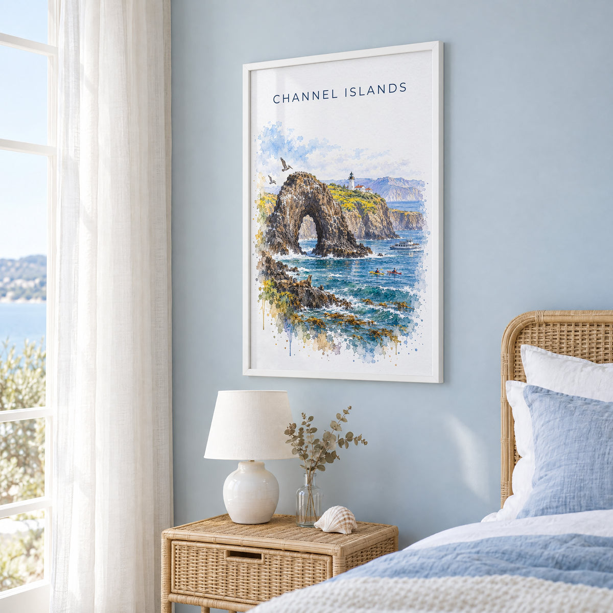 Channel Islands National Park watercolor print in a white frame on a pale blue wall beside a rattan bed in a coastal bedroom