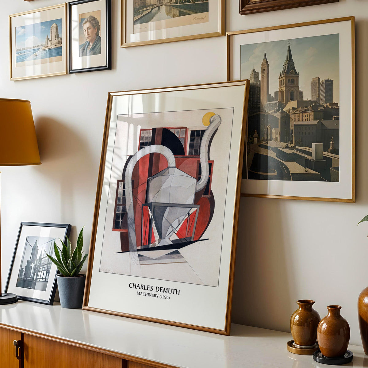 Demuth print shown in a gold frame leaning on a sideboard in a gallery wall
