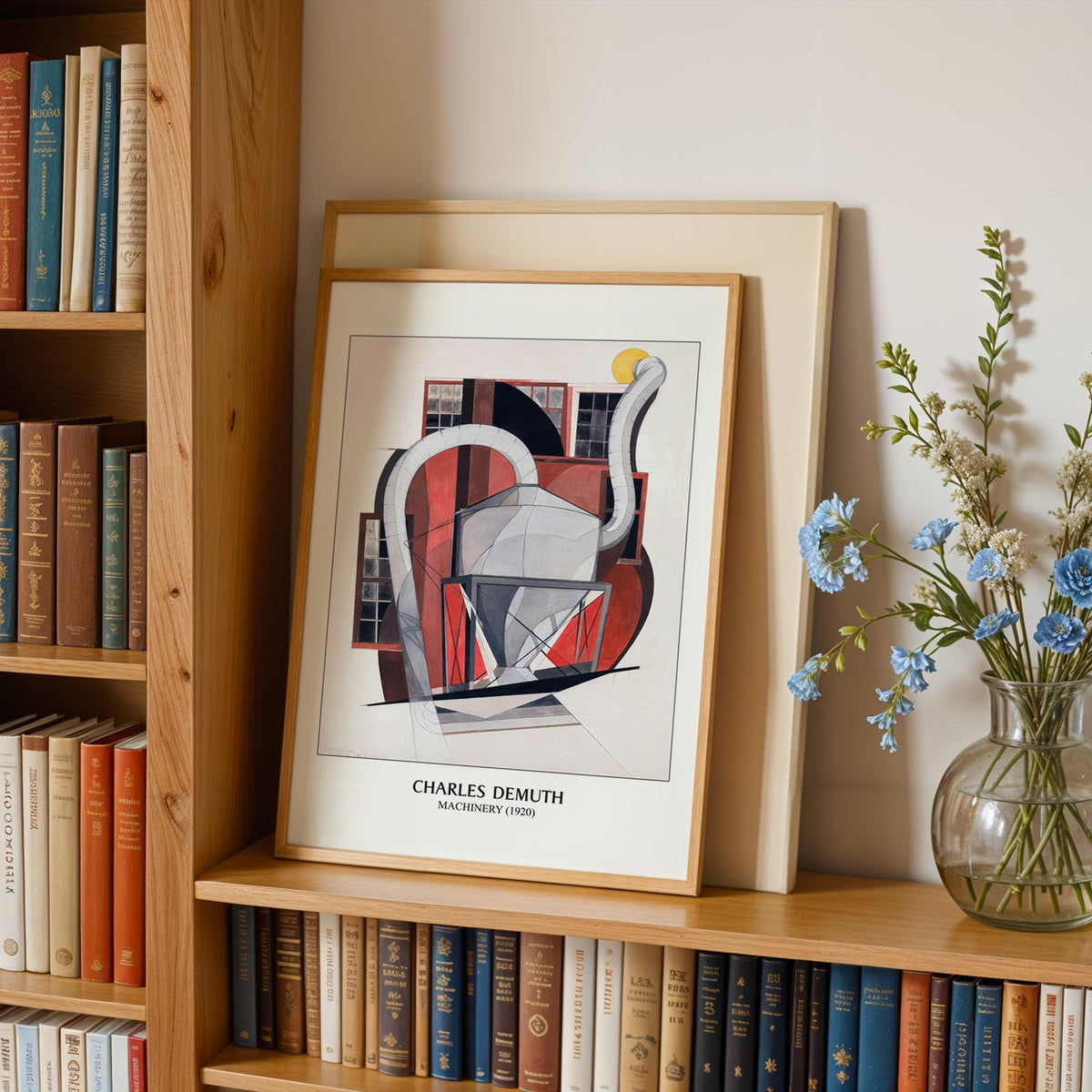 Factory print in an oak frame leaning on a bookshelf beside blue flowers