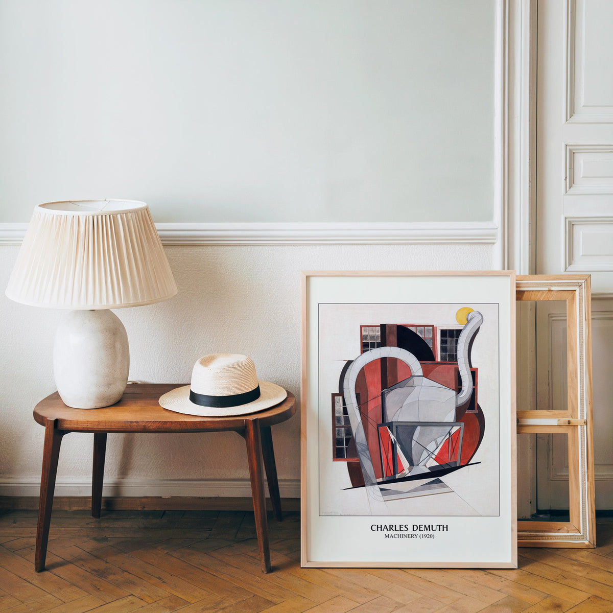 Precisionist poster in a light wood frame leaning by a bench and panama hat