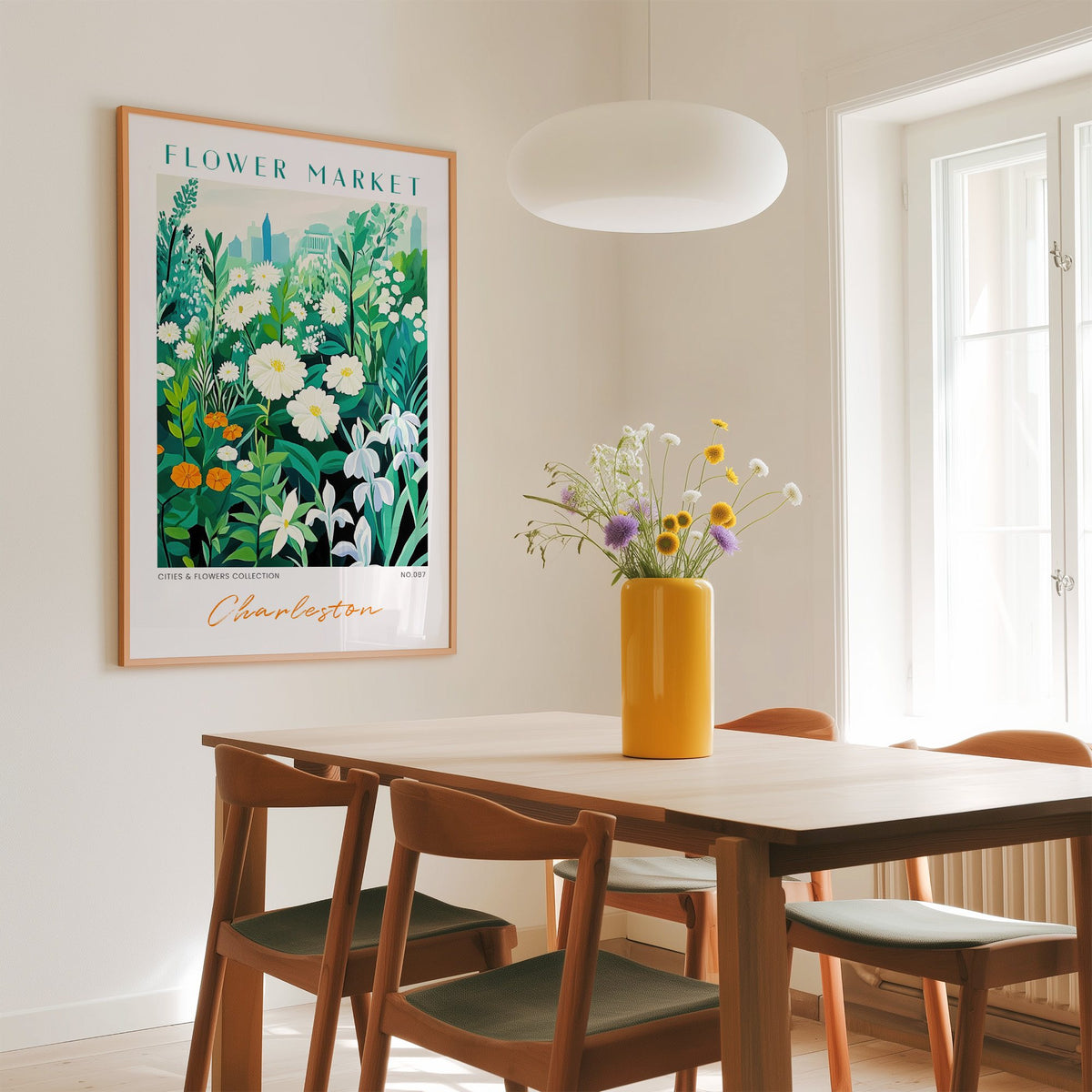 Charleston flower market print in an oak frame above a dining table with a yellow vase and white pendant light