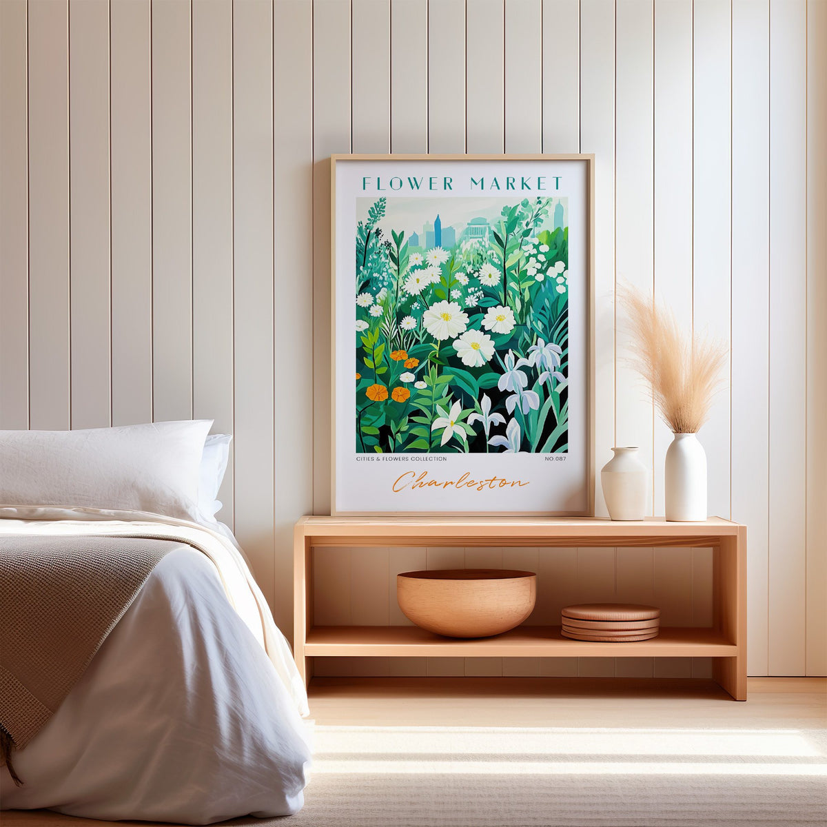 Charleston flower market print in an oak frame on a wood bench against a white shiplap bedroom wall with pampas grass