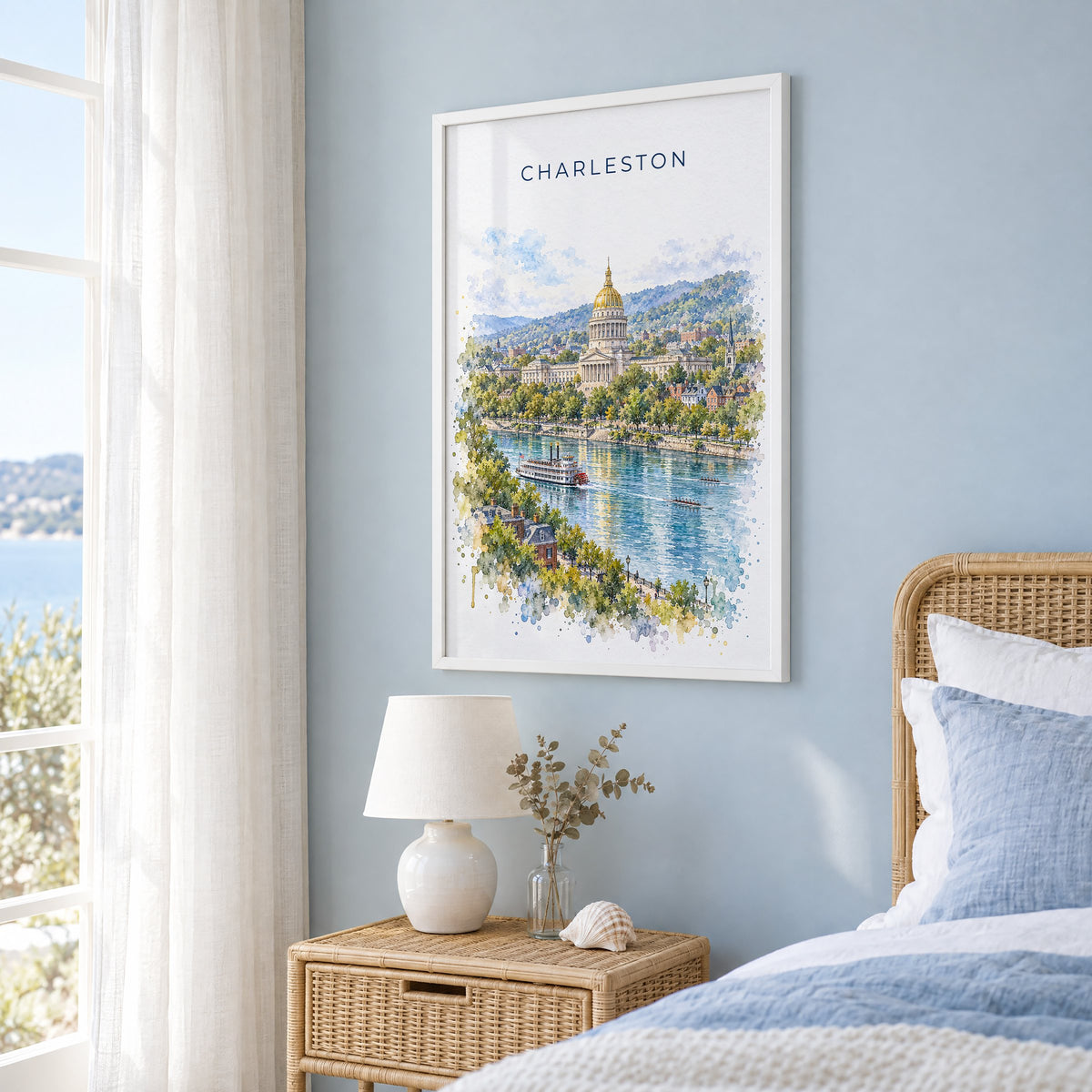 Charleston, West Virginia watercolor print in a white frame on a pale blue wall beside a rattan bed in a coastal bedroom