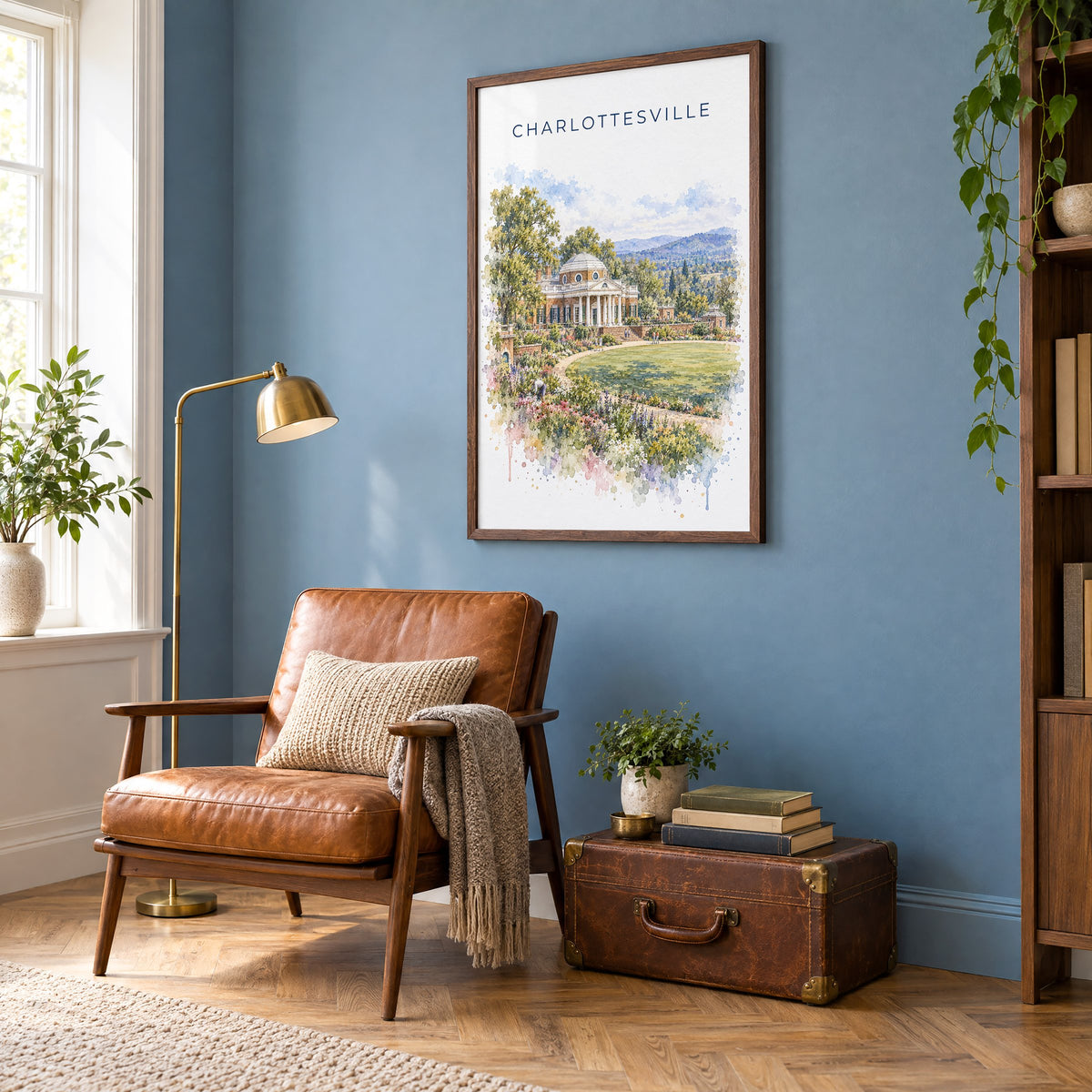 Charlottesville watercolor print in a walnut frame on a blue wall above a leather armchair in a reading nook