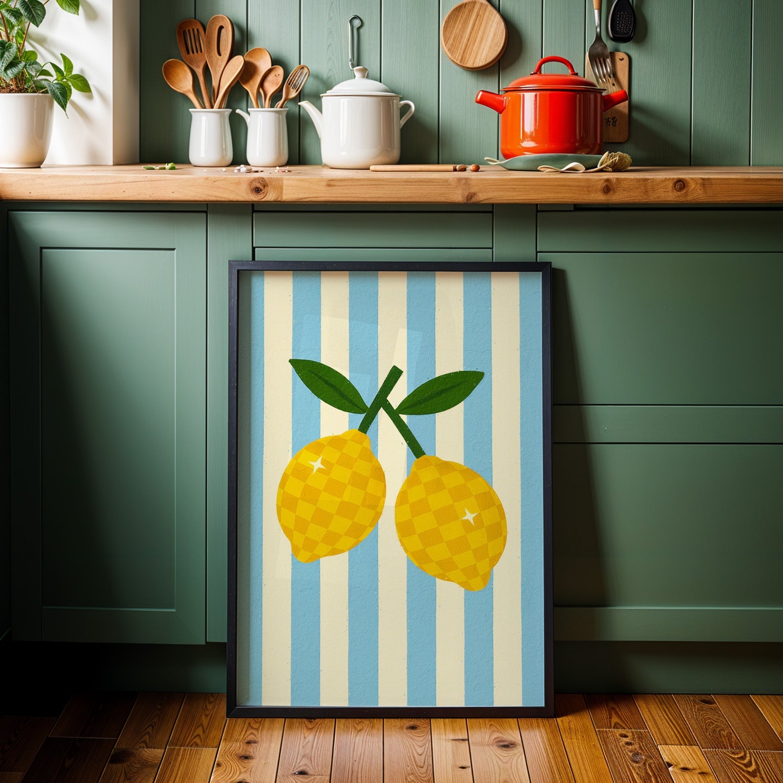 Checkered lemons print in a black frame against sage green kitchen cabinets