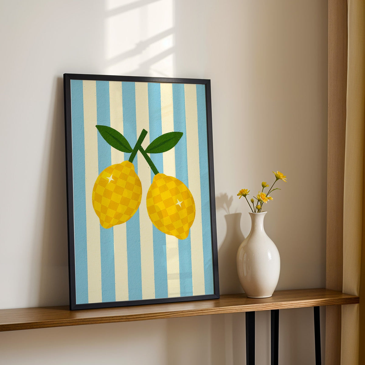 Checkered lemons print in a black frame on a console table with yellow daisies