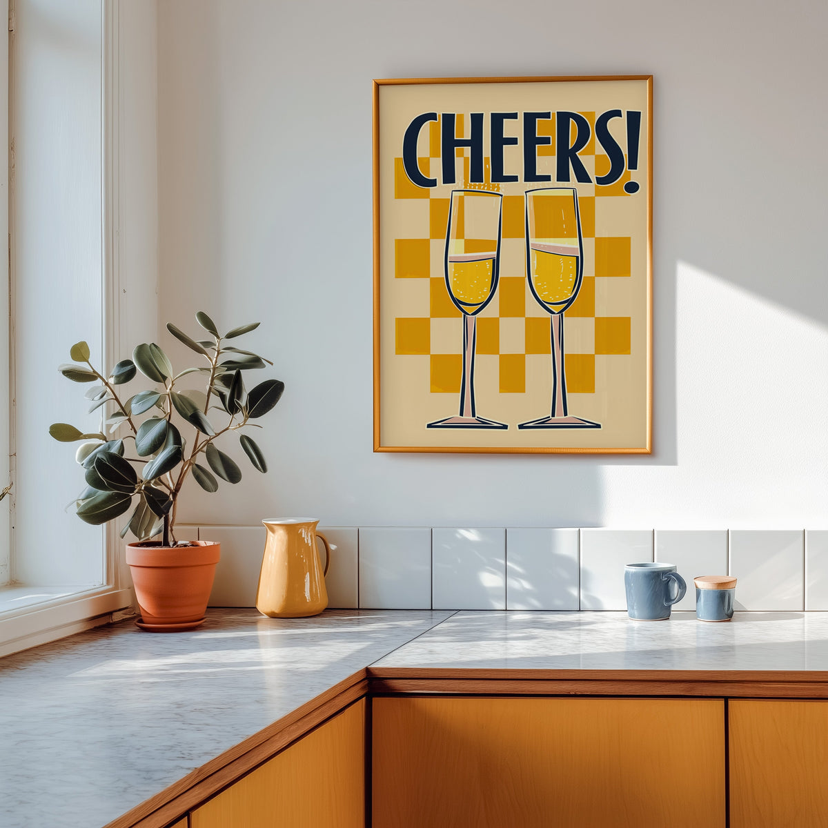 Cheers champagne flutes print shown in a gold frame above a marble counter in a tan kitchen