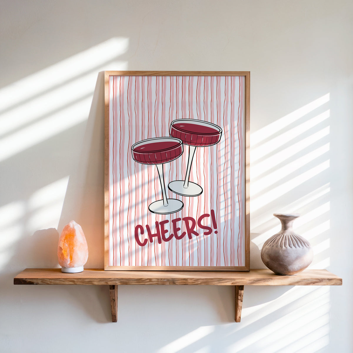 Cheers coupes print in an oak frame on a live-edge shelf beside a salt lamp