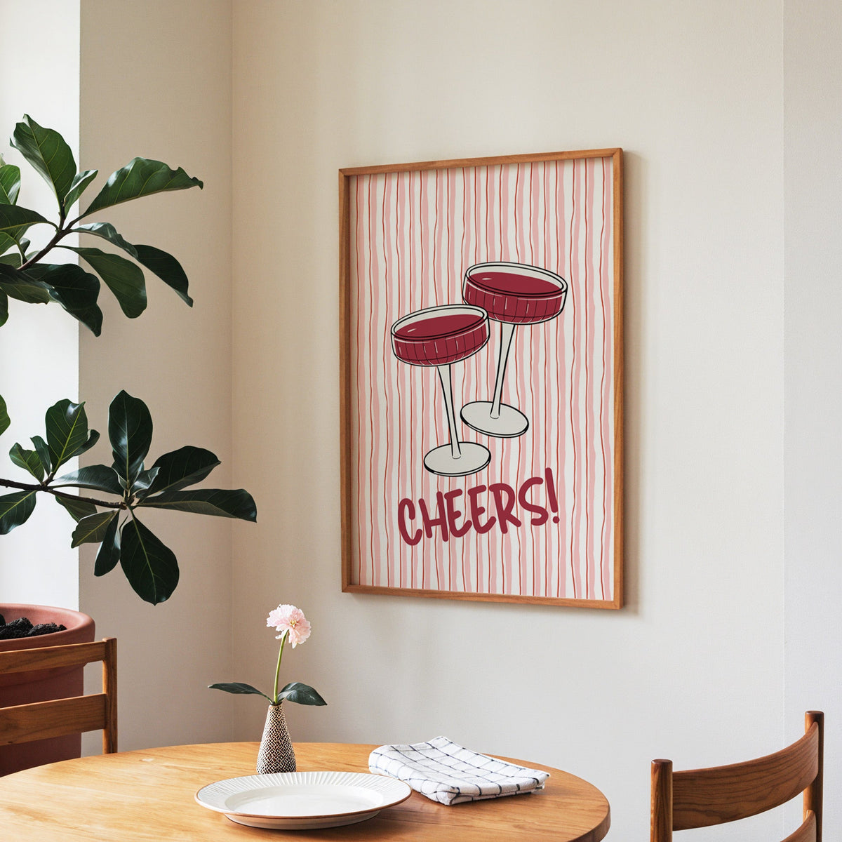 Cheers coupes print in a walnut frame above a round table beside a fiddle-leaf fig