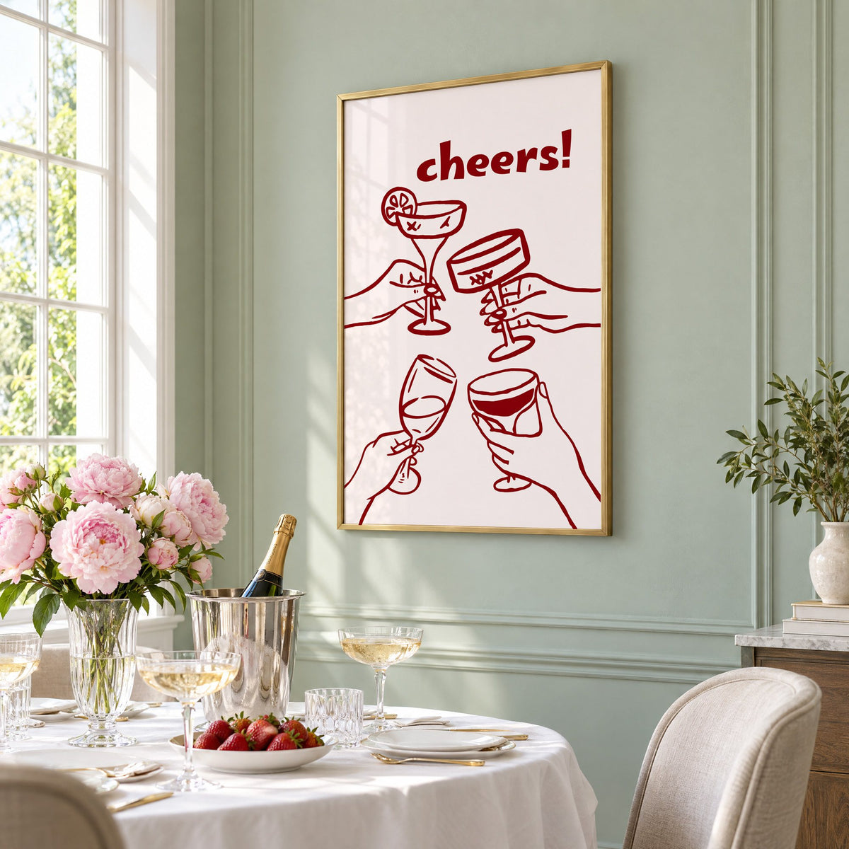cheers! four hands toasting burgundy line print in a brass frame on a sage wall above a brunch table with champagne and peonies, seen at an angle