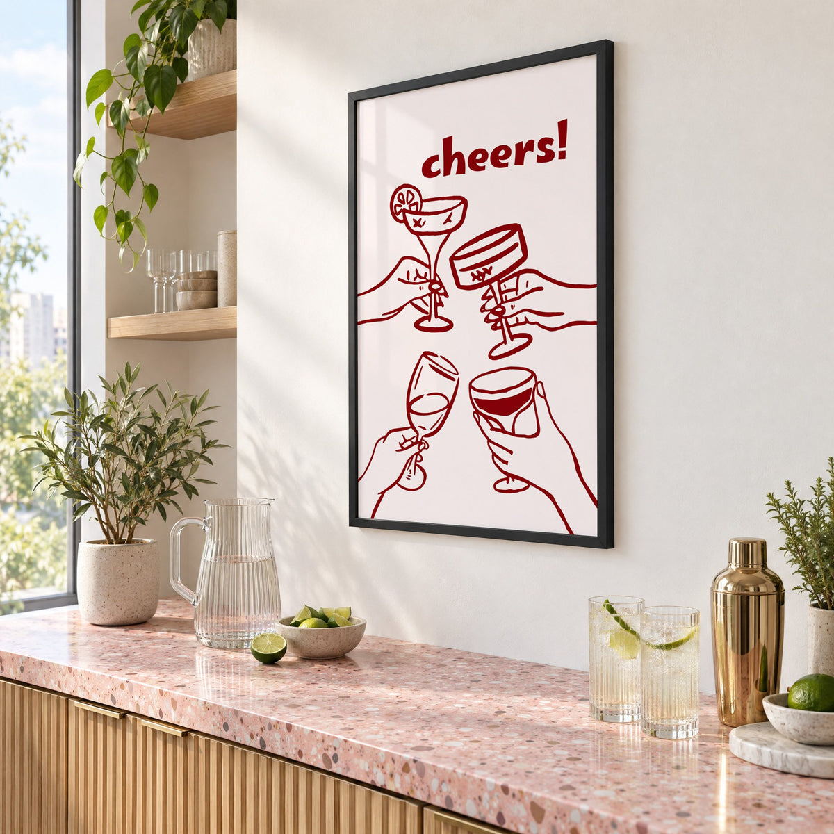 cheers! four hands toasting burgundy line print in a black frame above a pink terrazzo cocktail counter with limes, seen at an angle
