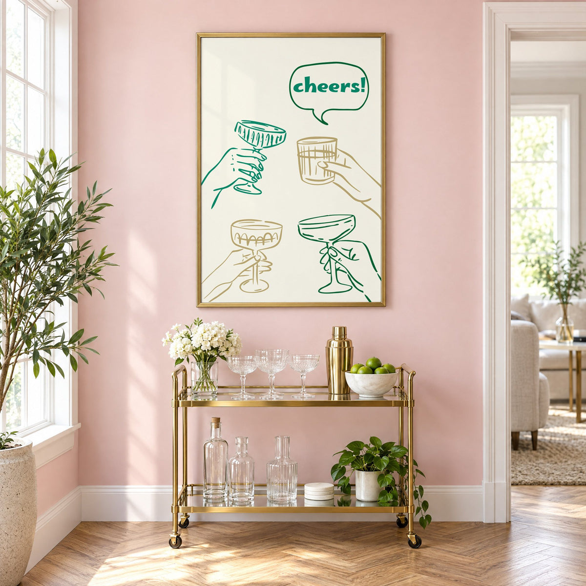 cheers! hands toasting coupes teal and gold print in a brass frame on a blush pink wall above a gold bar cart with glassware