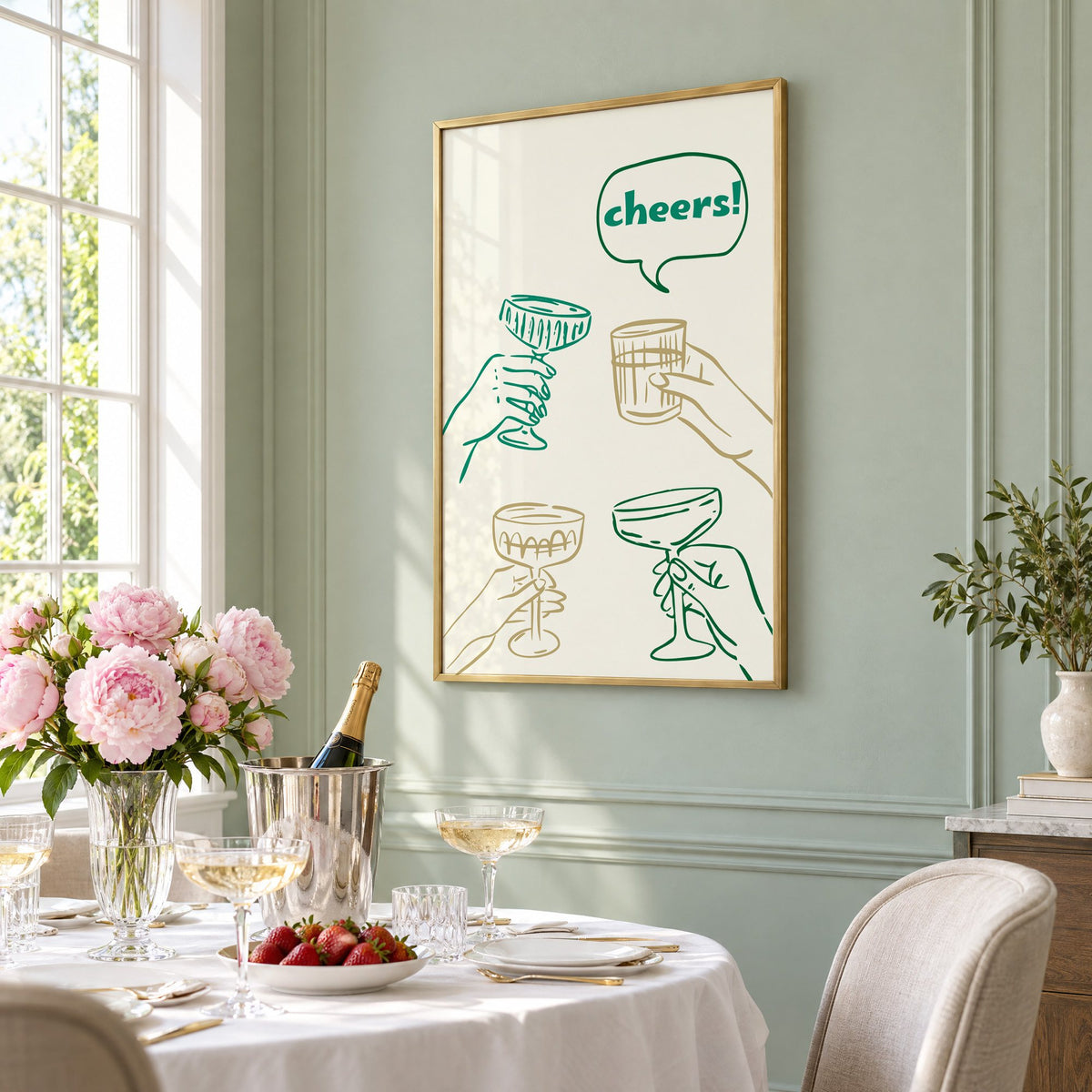 cheers! hands toasting coupes teal and gold print in a brass frame on a sage wall above a brunch table with champagne and peonies, seen at an angle