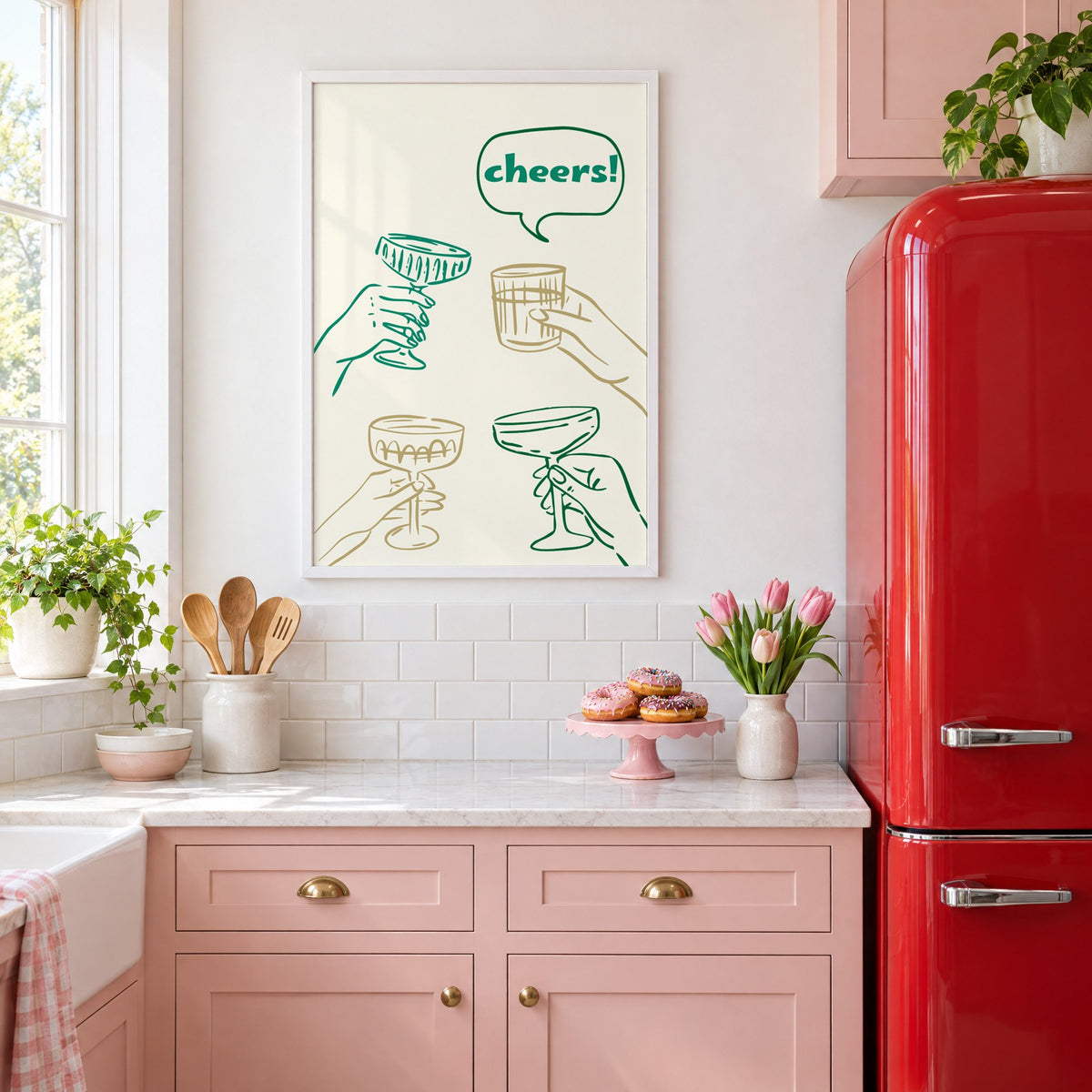 cheers! hands toasting coupes teal and gold print in a white frame above pink cabinets beside a red retro fridge