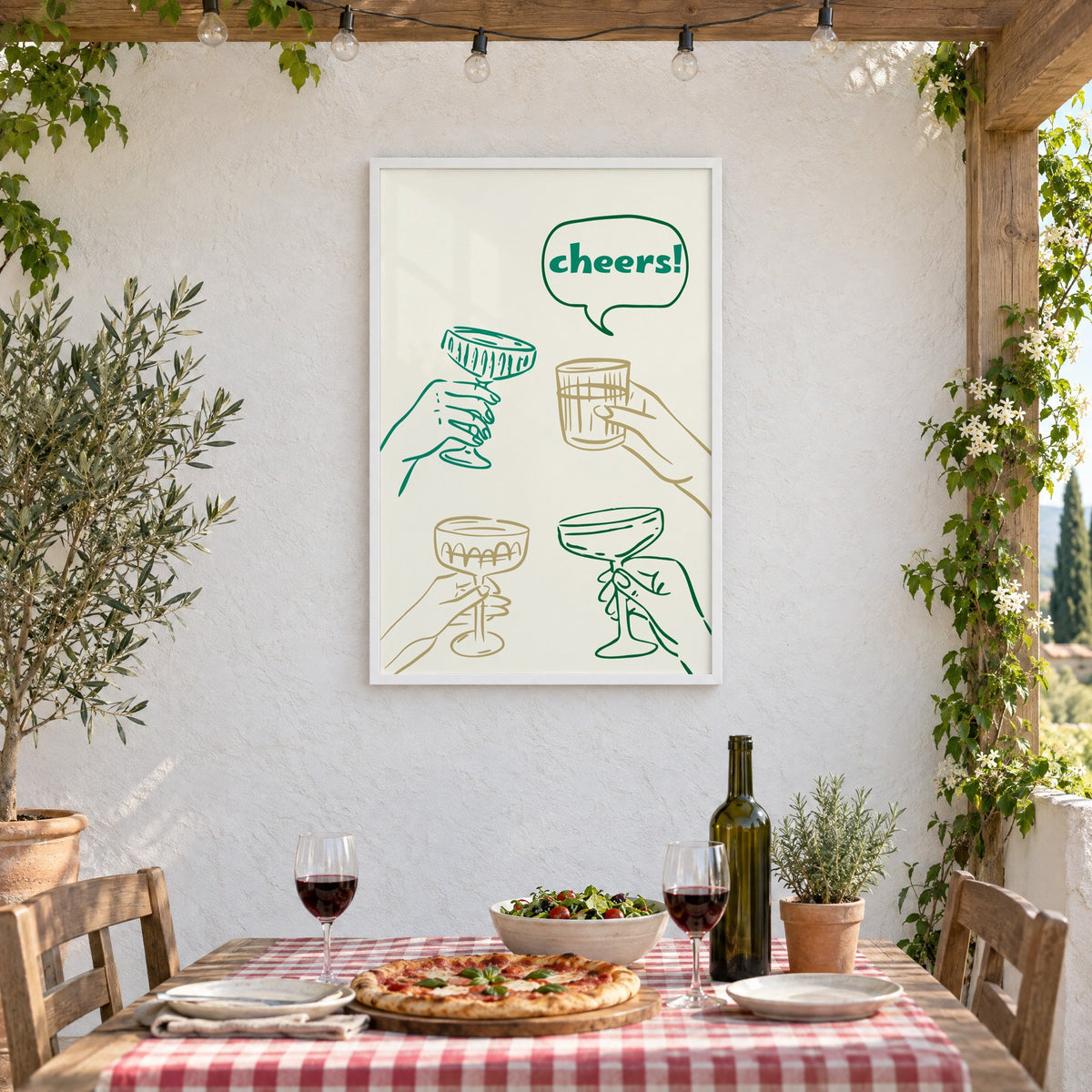 cheers! hands toasting coupes teal and gold print in a white frame on a stucco wall above a checked-cloth table with pizza and red wine