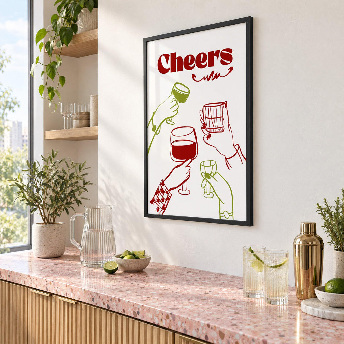 Cheers red and olive toasting hands print in a black frame above a pink terrazzo cocktail counter with limes, seen at an angle