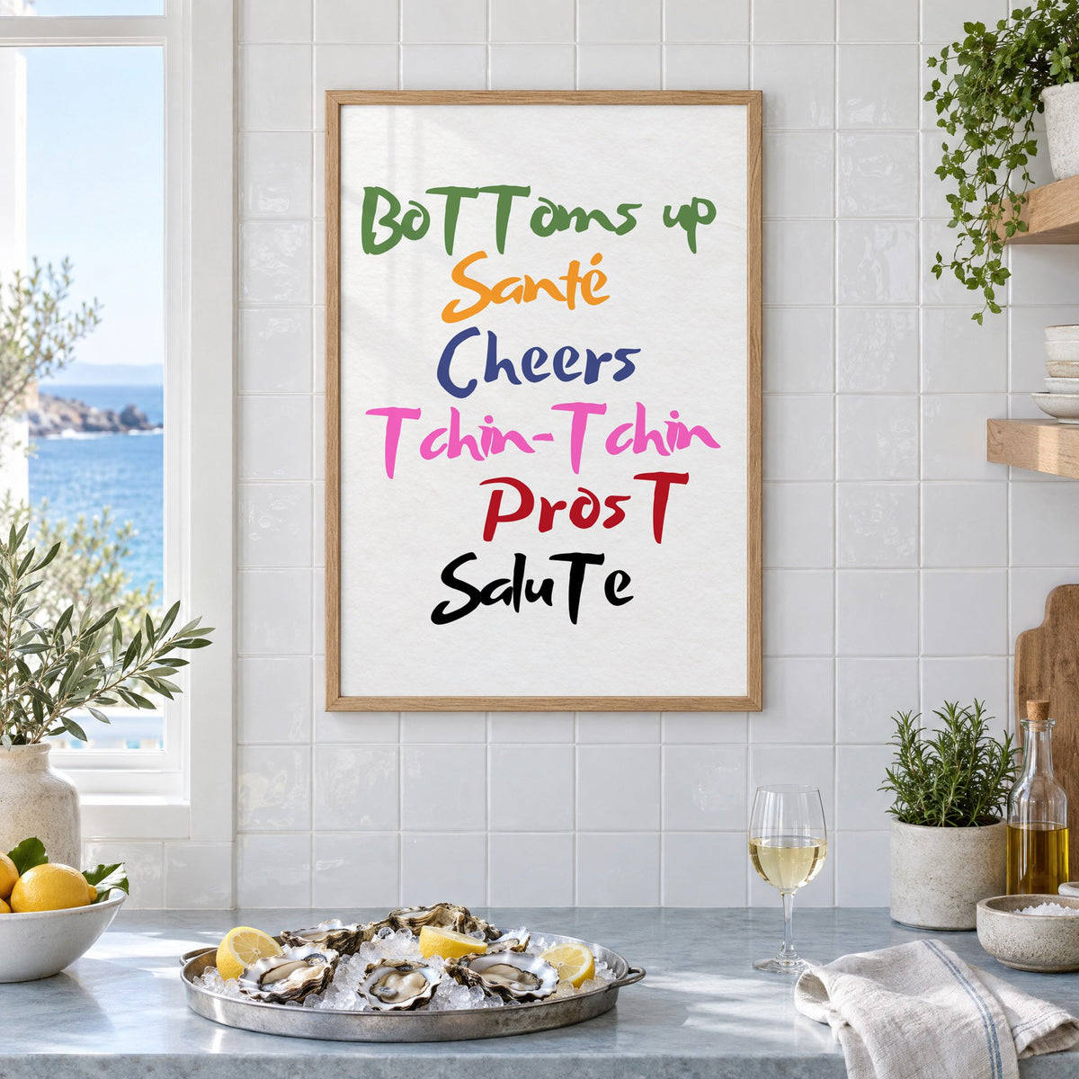 Cheers in six languages brush lettering print in an oak frame on white tiles above a marble counter with oysters and lemons by a sea view