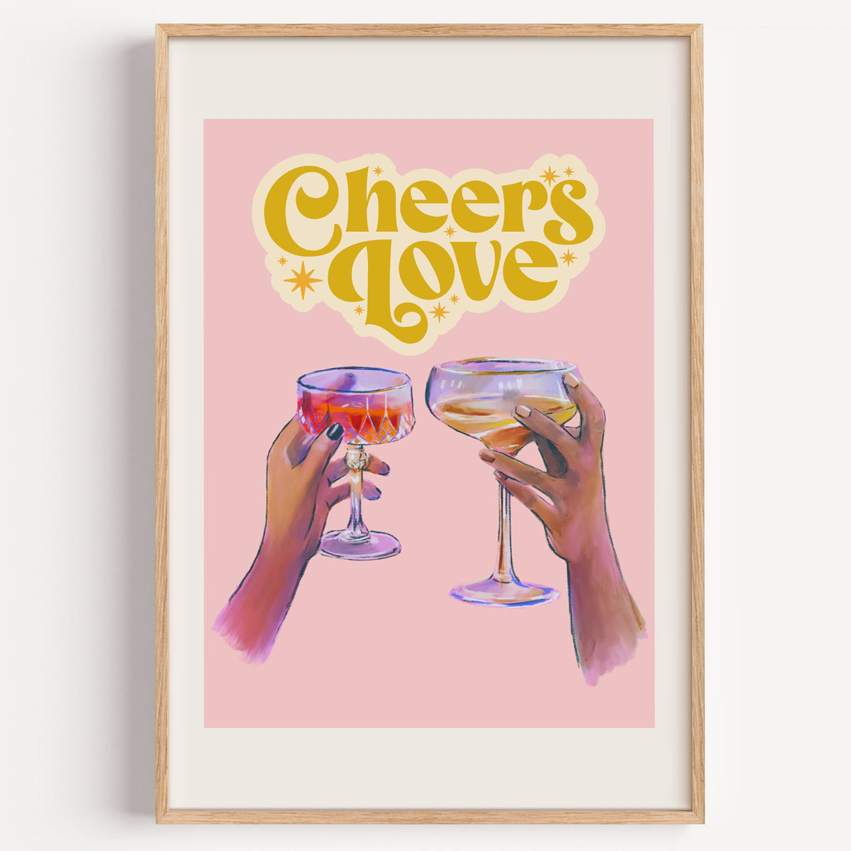 Cheers Love coupe toast print in a light oak frame on a plain white wall
