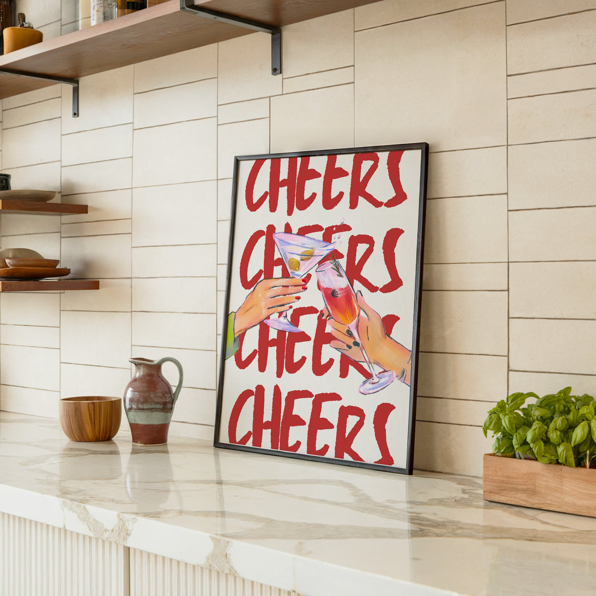 Cheers repeat type print in a black frame leaning on a marble counter in a tiled kitchen