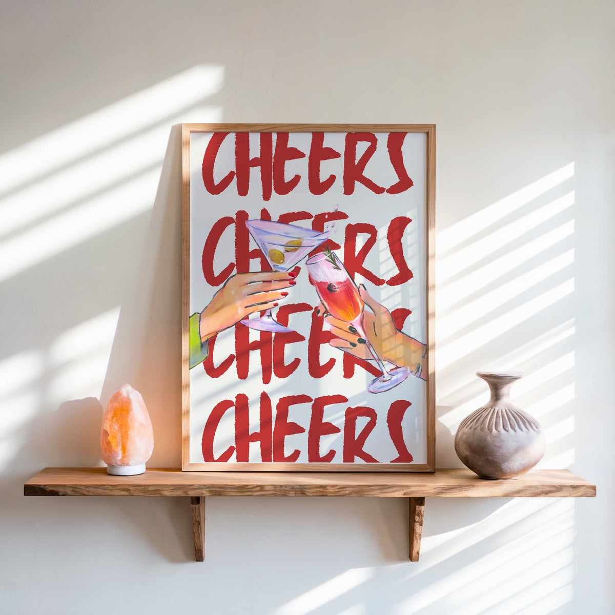 Cheers repeat type print in an oak frame on a live-edge shelf beside a salt lamp