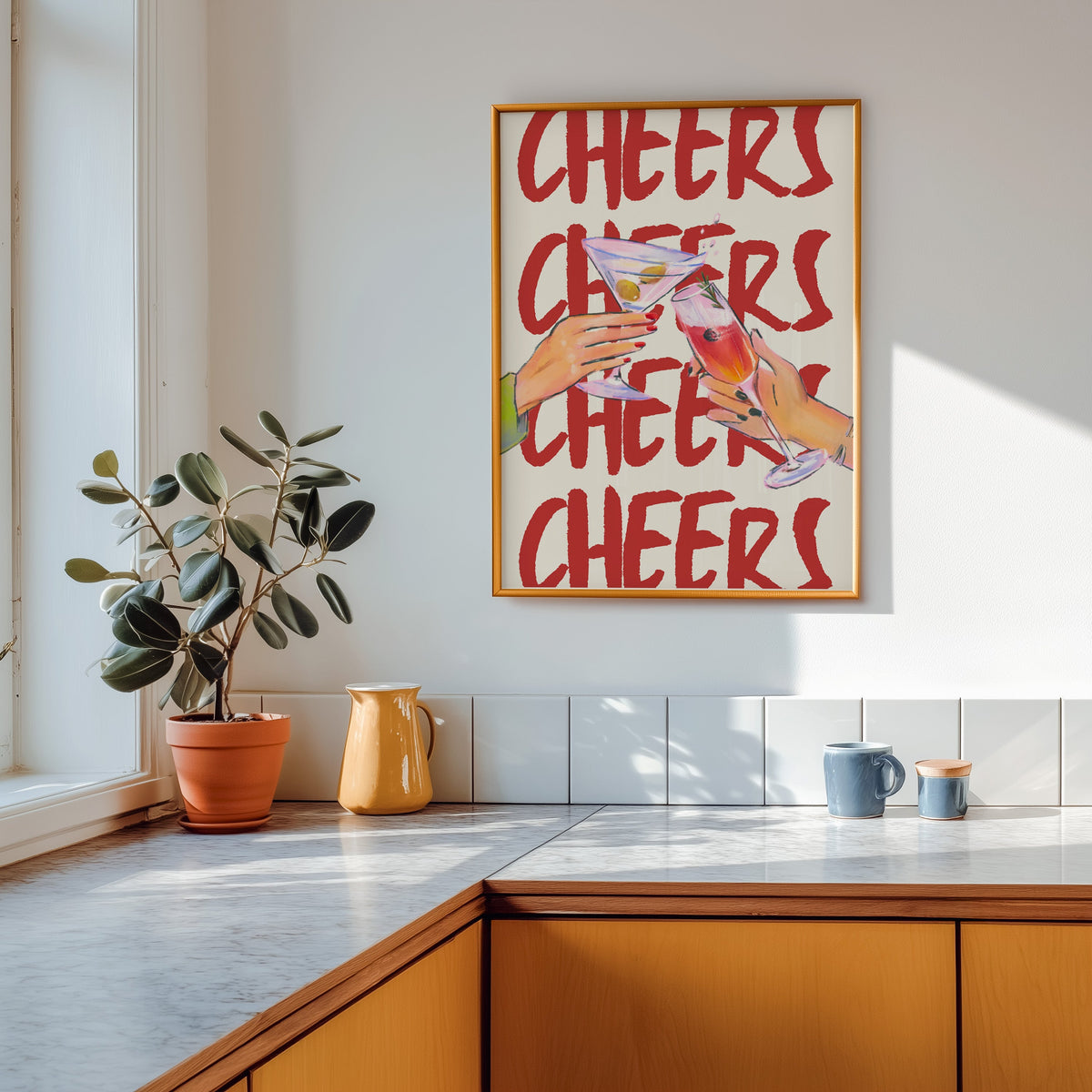 Cheers repeat type print shown in a gold frame above a marble counter in a tan kitchen
