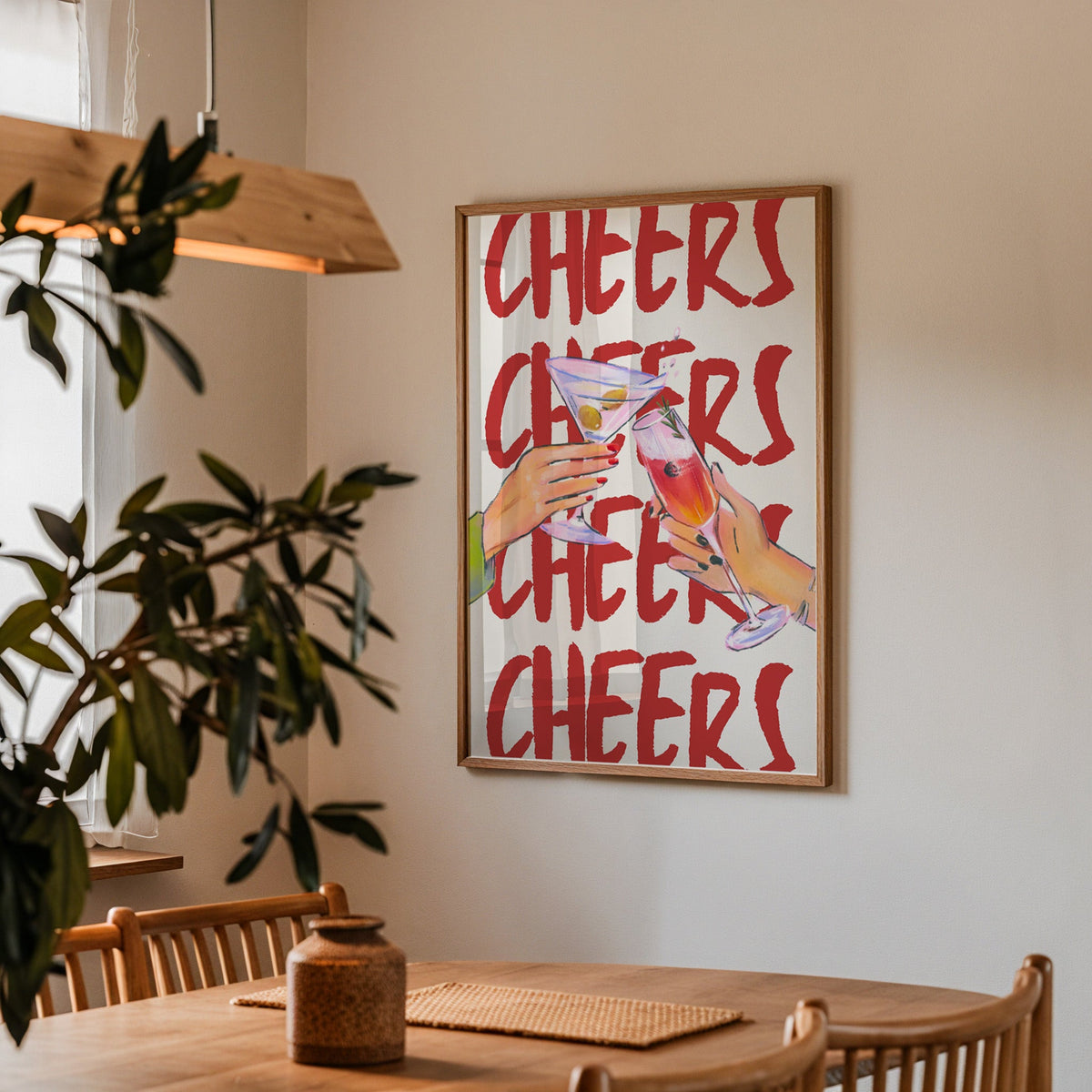 Cheers repeat type print in a walnut frame above a dining table with olive branches