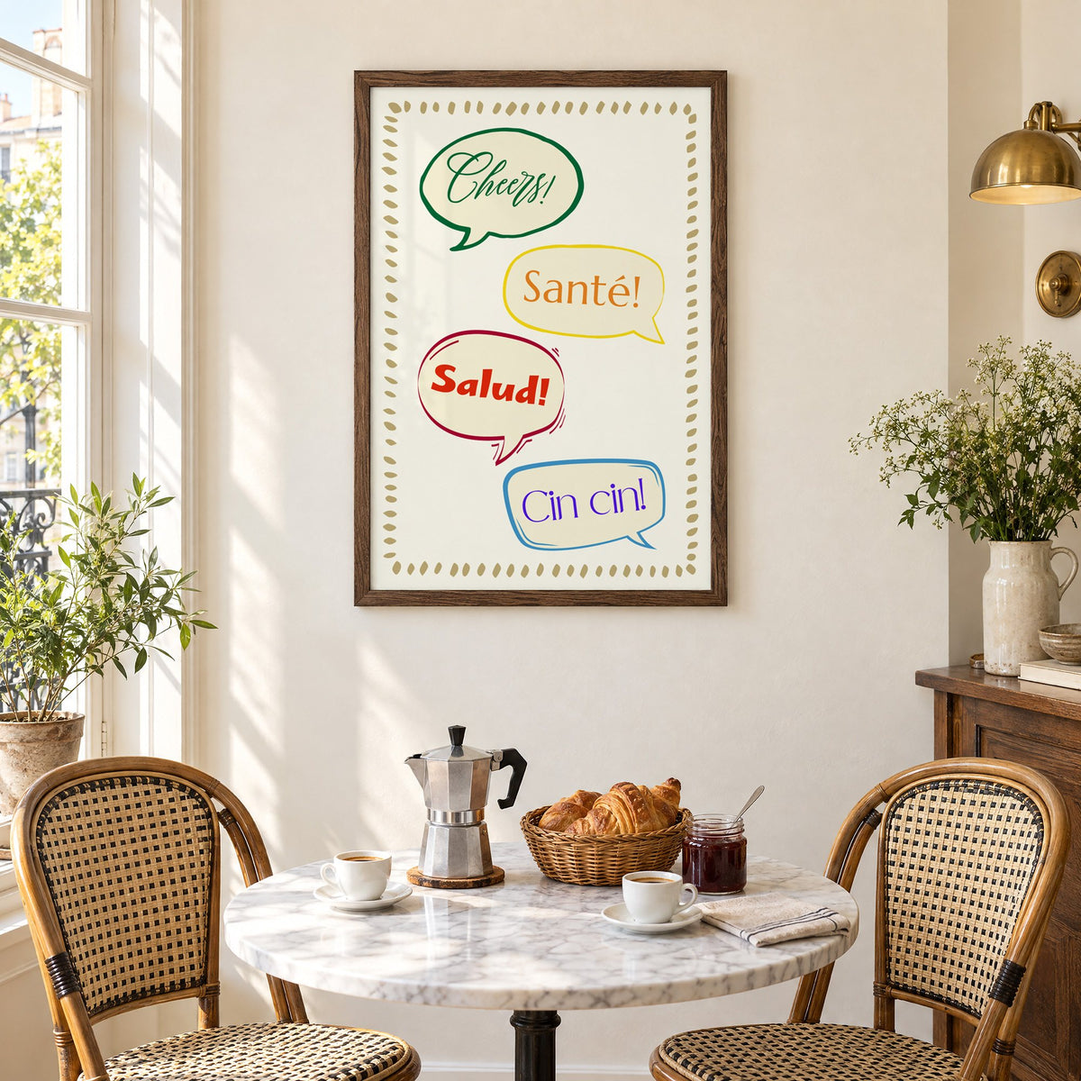 Cheers! Santé! Salud! Cin cin! speech bubbles print in a walnut frame above a marble bistro table with croissants and rattan chairs