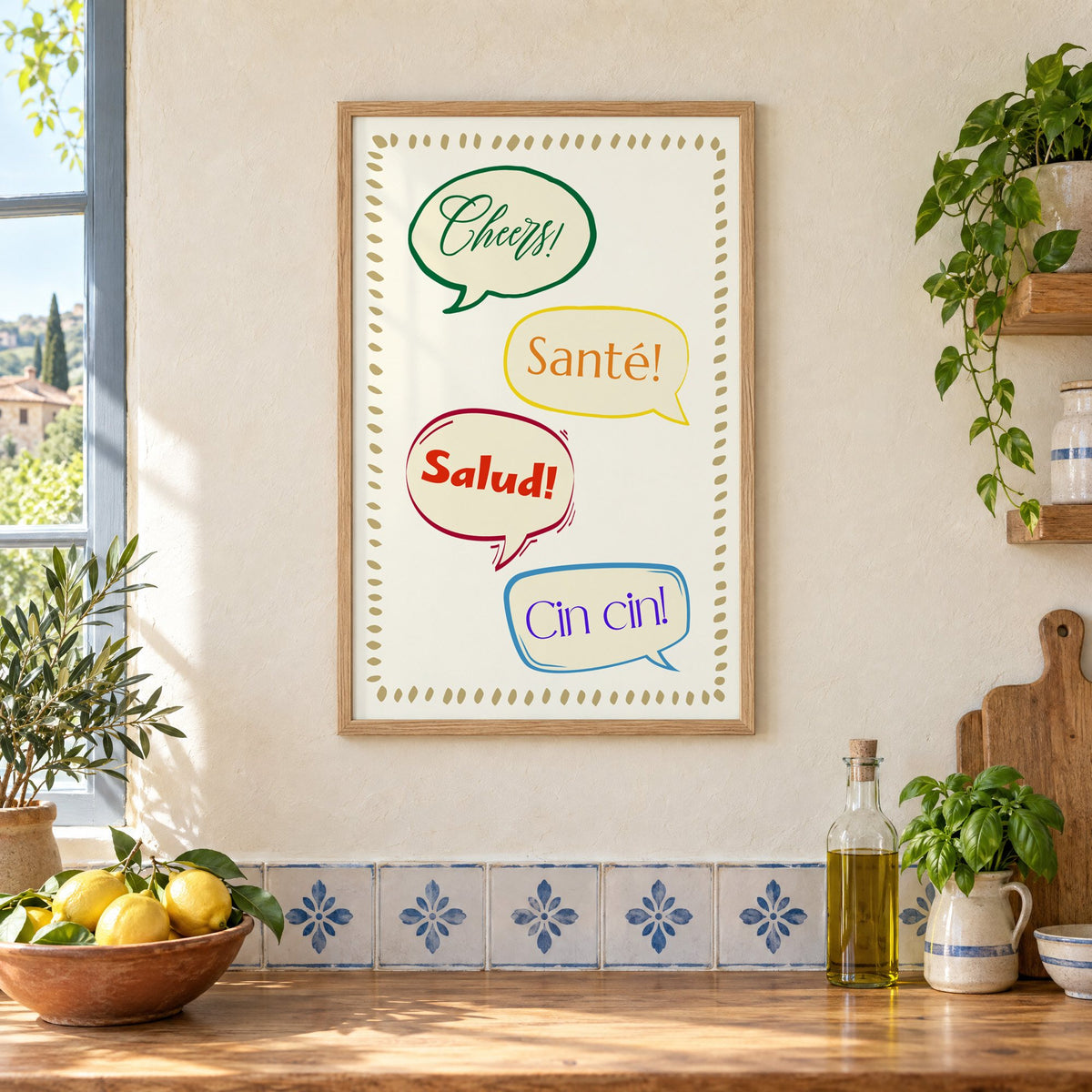 Cheers! Santé! Salud! Cin cin! speech bubbles print in an oak frame on a cream plaster wall above a worktop with a bowl of lemons and blue-and-white tiles
