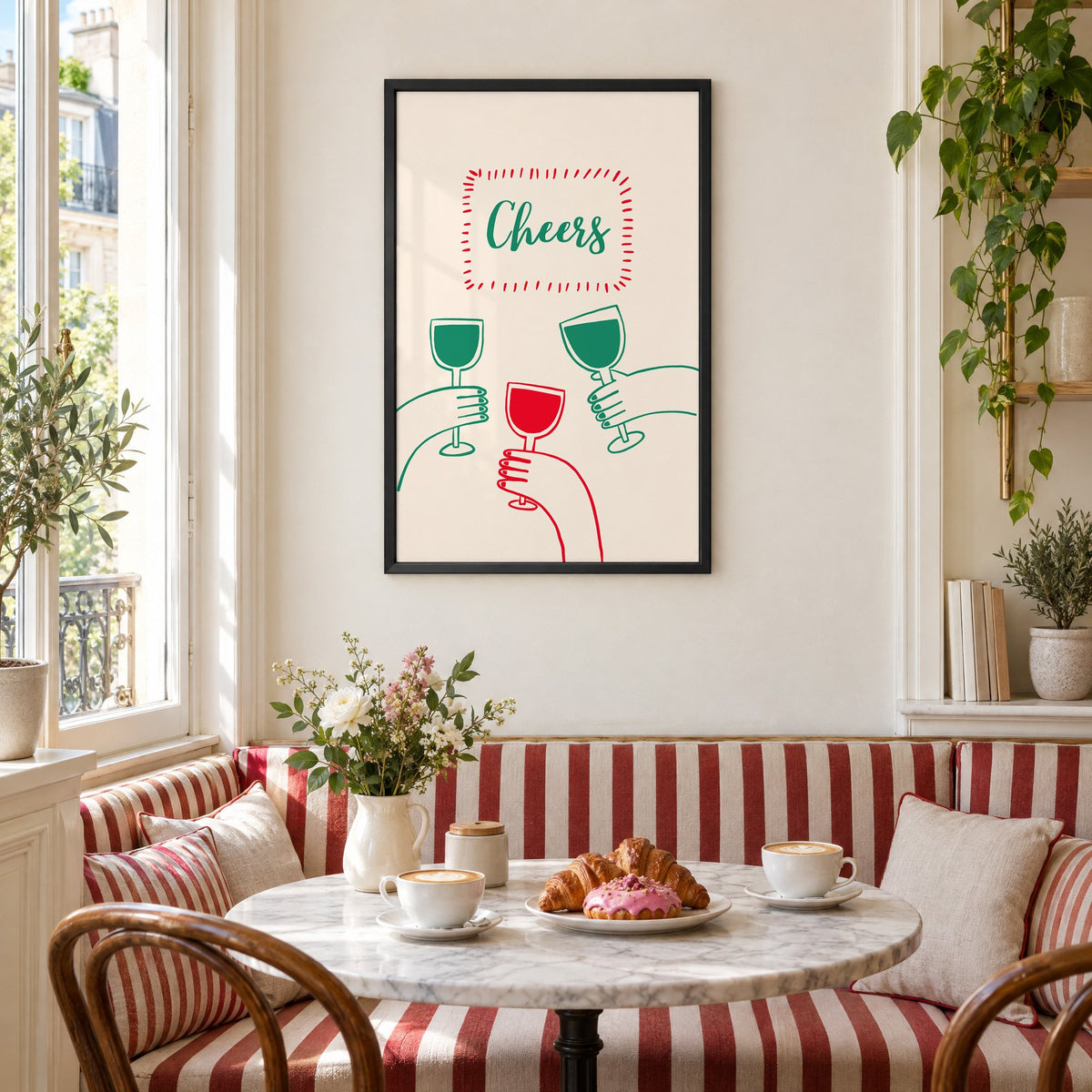 Cheers three hands wine toast line print in a black frame above a striped cafe breakfast nook with cappuccino and pastries