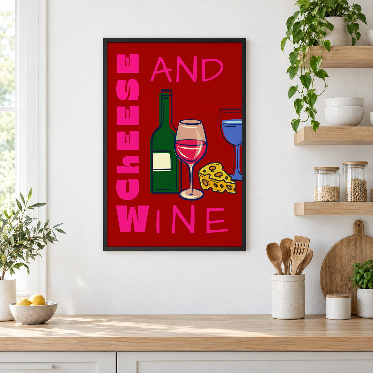 Cheese and wine bold red pink print in a black frame in a white kitchen beside open wood shelves and glass jars